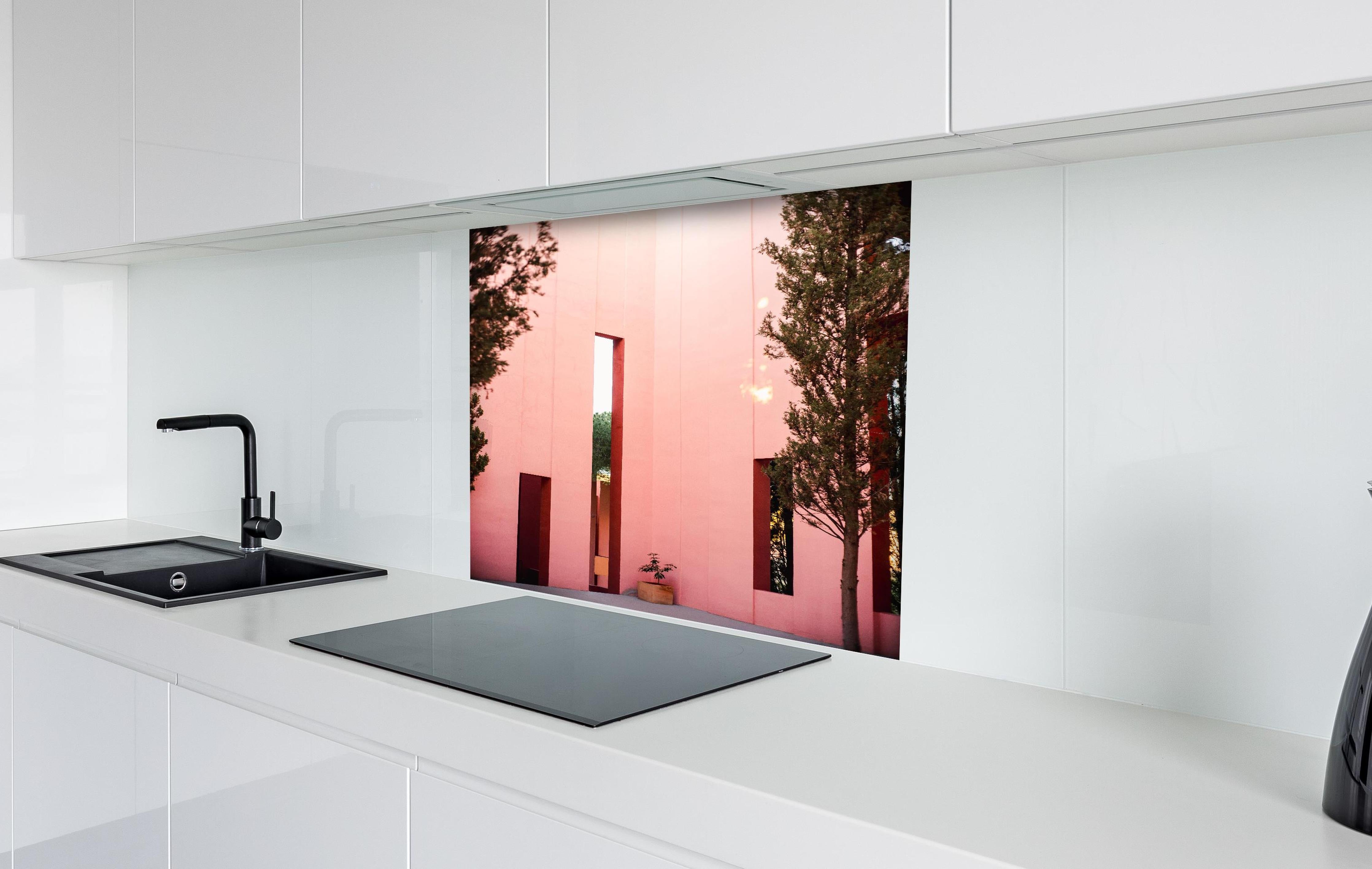 Spritzschutz - Muralla Roja Eingang in zartem Pink hinter einem Cerankochfeld zwischen Holz-Kochutensilien
