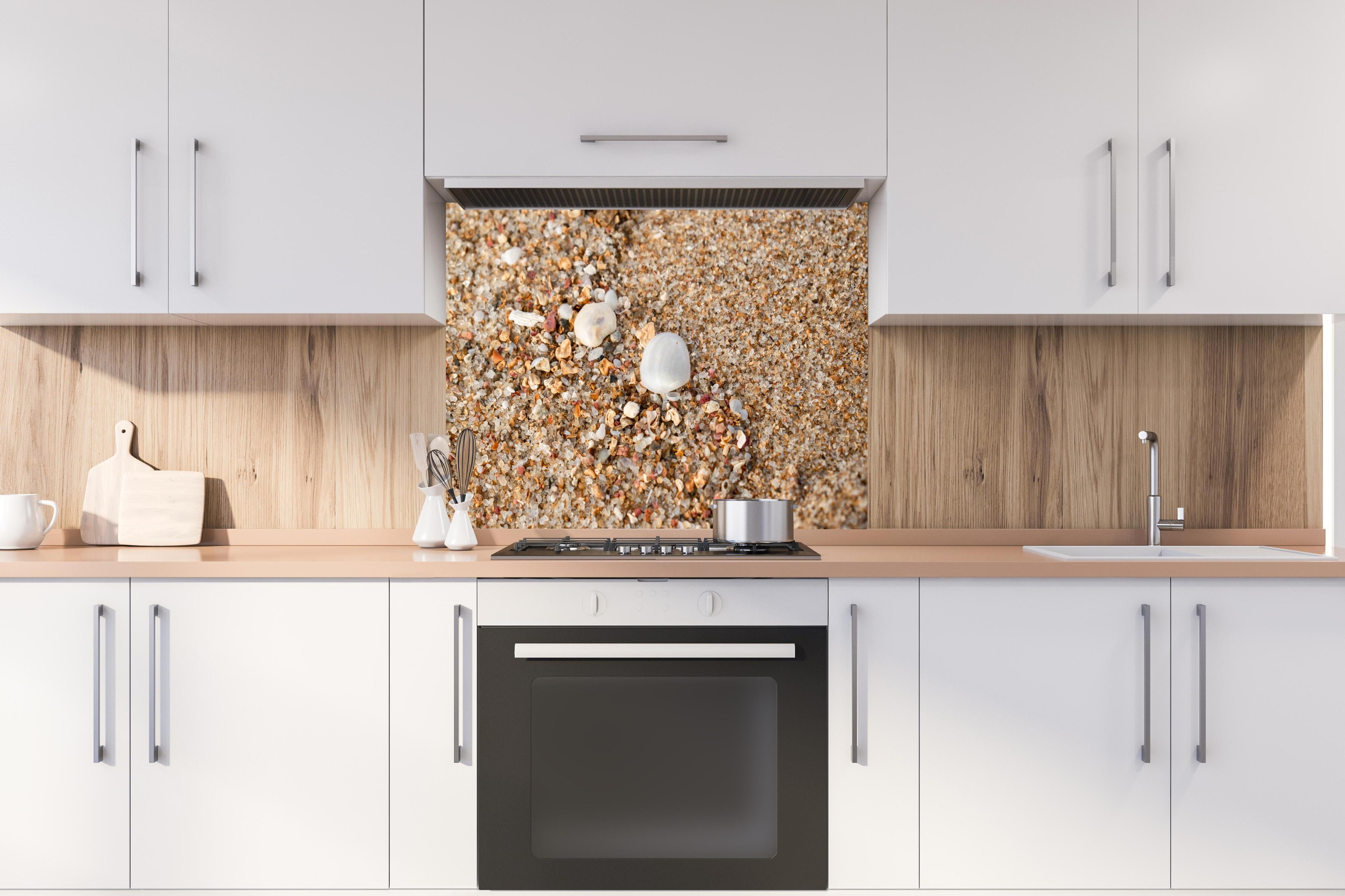 Spritzschutz - Muscheln im Strandsand. Shell hinter einem Cerankochfeld zwischen Holz-Kochutensilien
