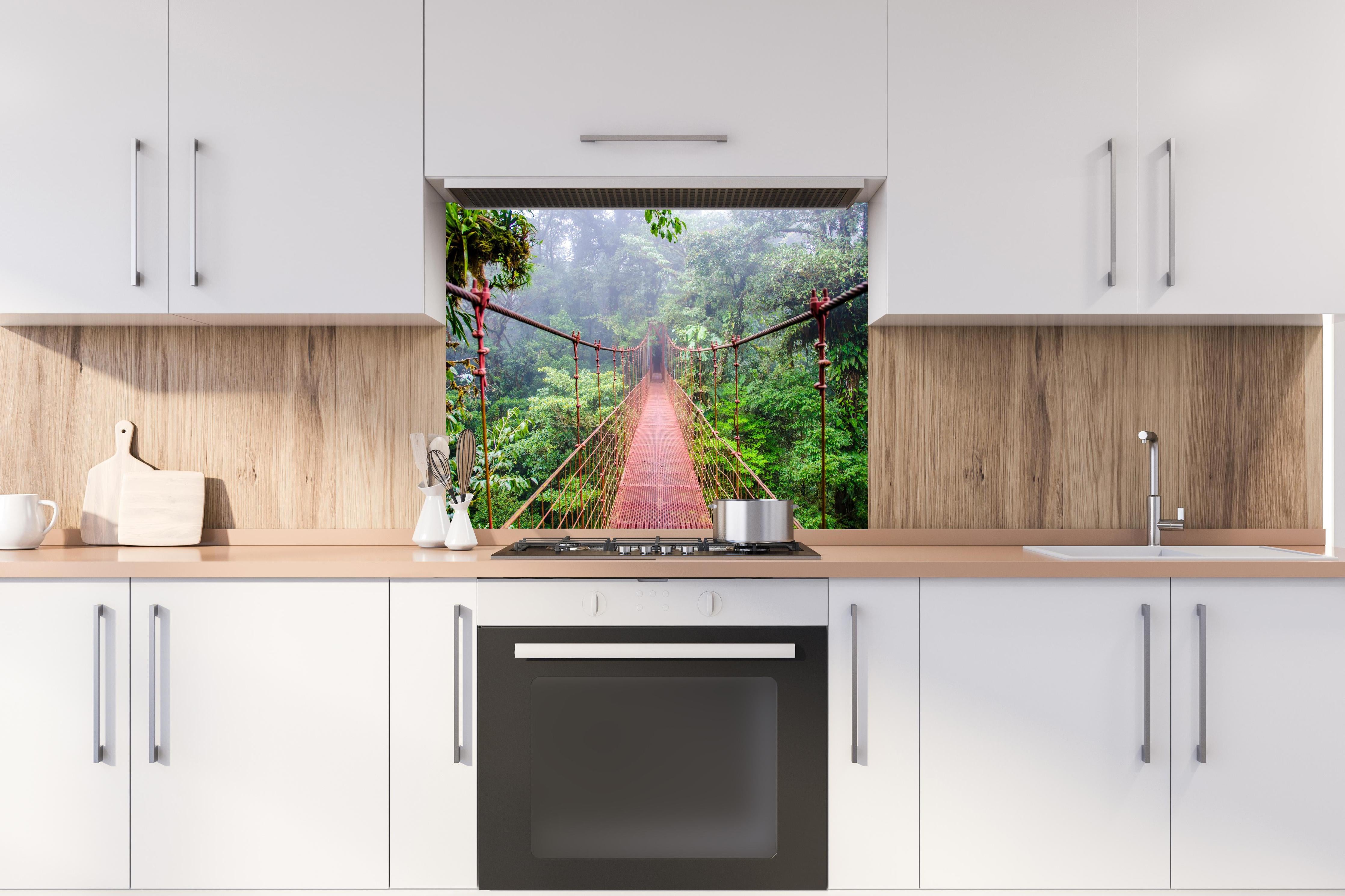 Spritzschutz - Mystische Hängebrücke im nebeligen Regenwald hinter einem Cerankochfeld zwischen Holz-Kochutensilien
