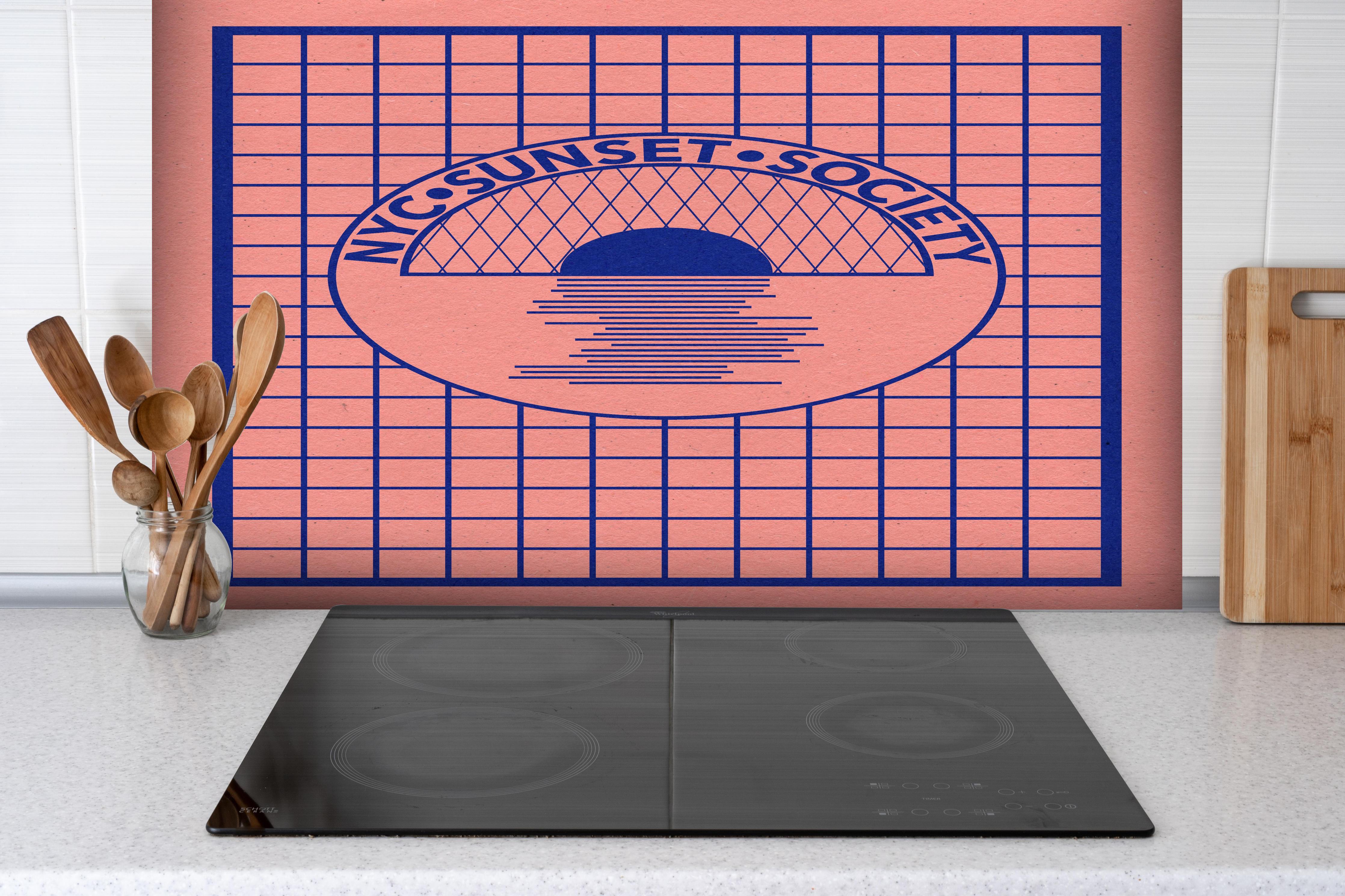 Spritzschutz - NYC Sunset Society Papierkunstwerk hinter einem Cerankochfeld zwischen Holz-Kochutensilien
