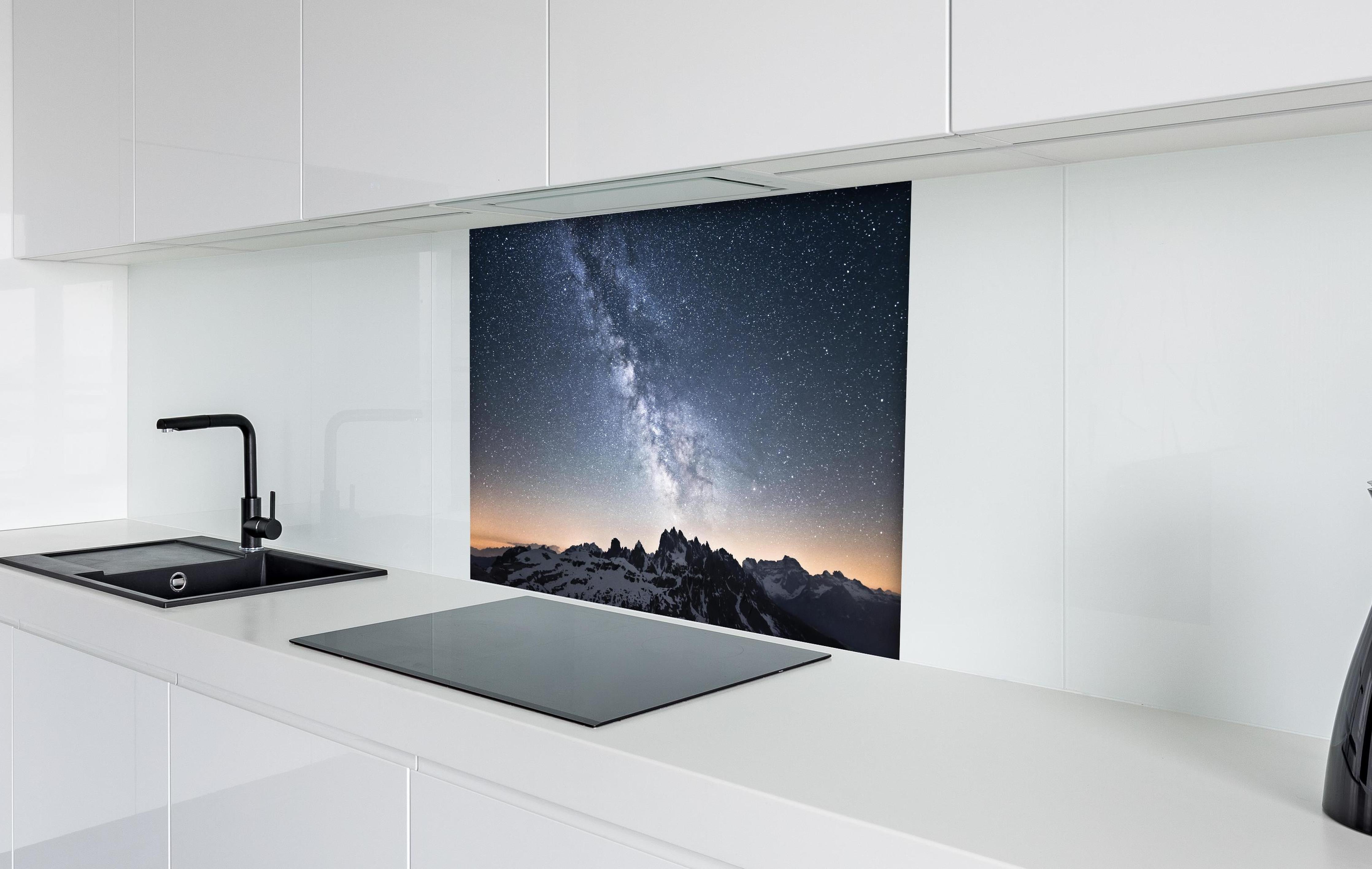 Spritzschutz - Nachthimmel Sterne Schneeberge Panorama hinter einem Cerankochfeld zwischen Holz-Kochutensilien

