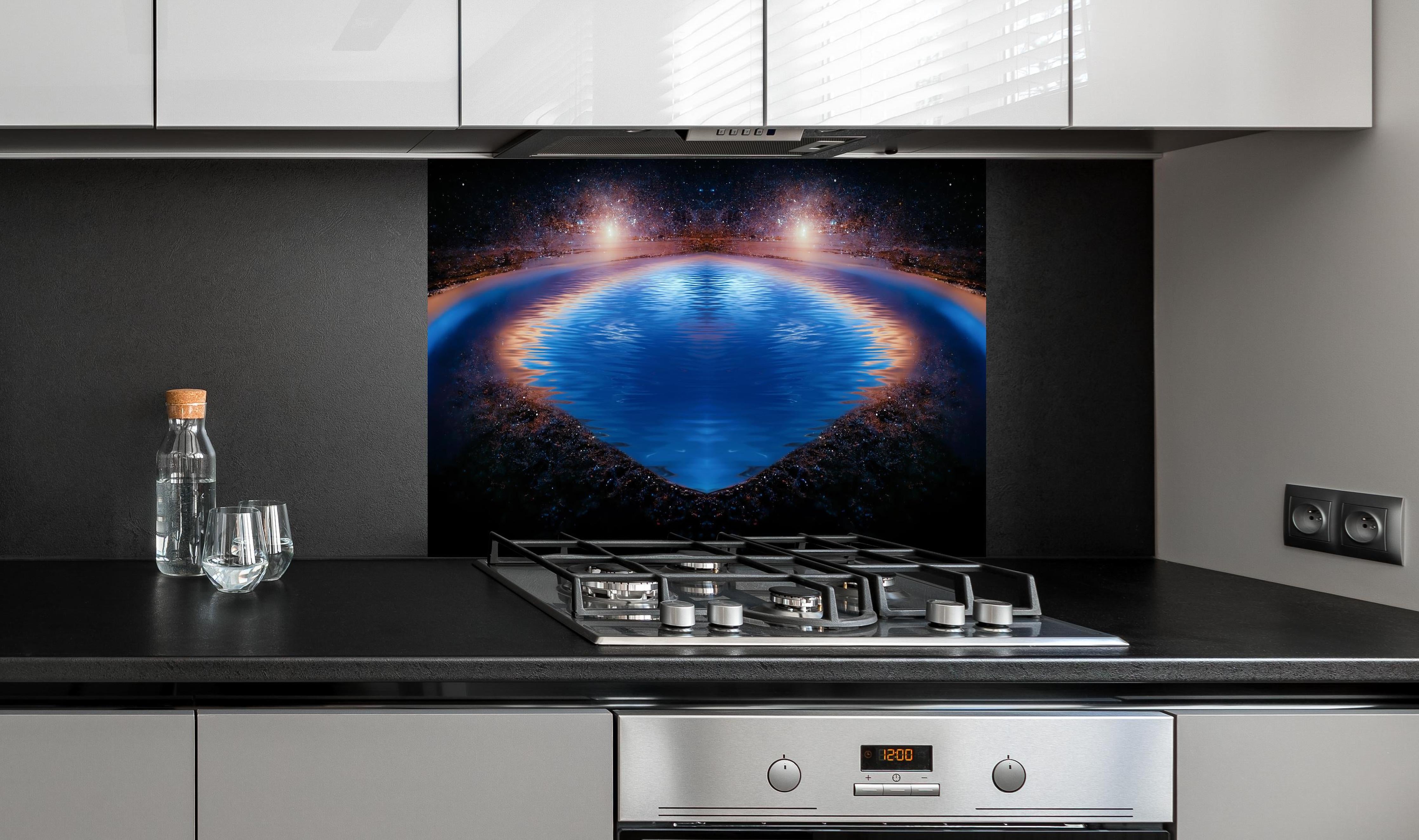 Spritzschutz - Nächtliche Fantasielandschaft hinter einem Cerankochfeld zwischen Holz-Kochutensilien
