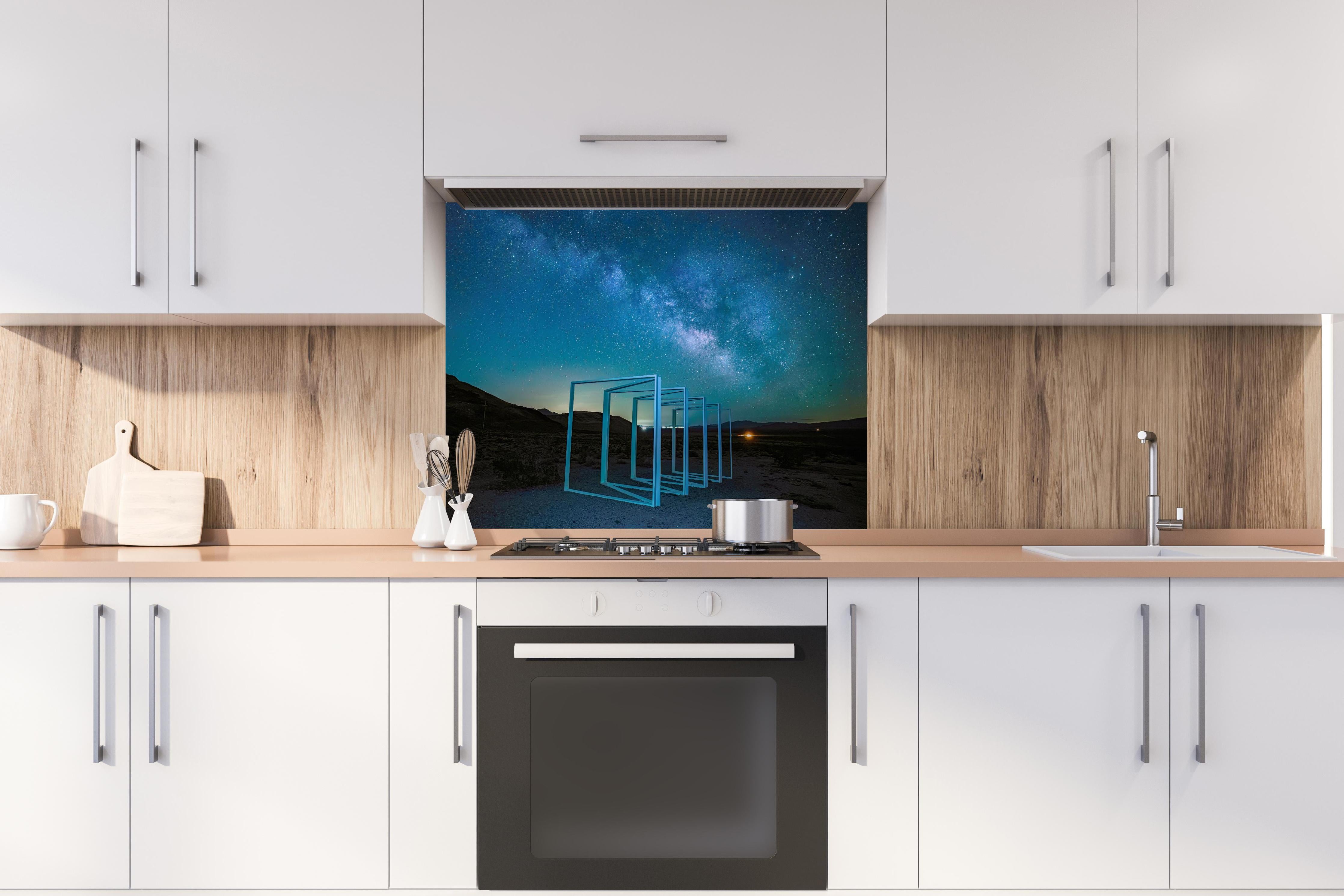 Spritzschutz - Nächtliche Landschaft  hinter einem Cerankochfeld zwischen Holz-Kochutensilien
