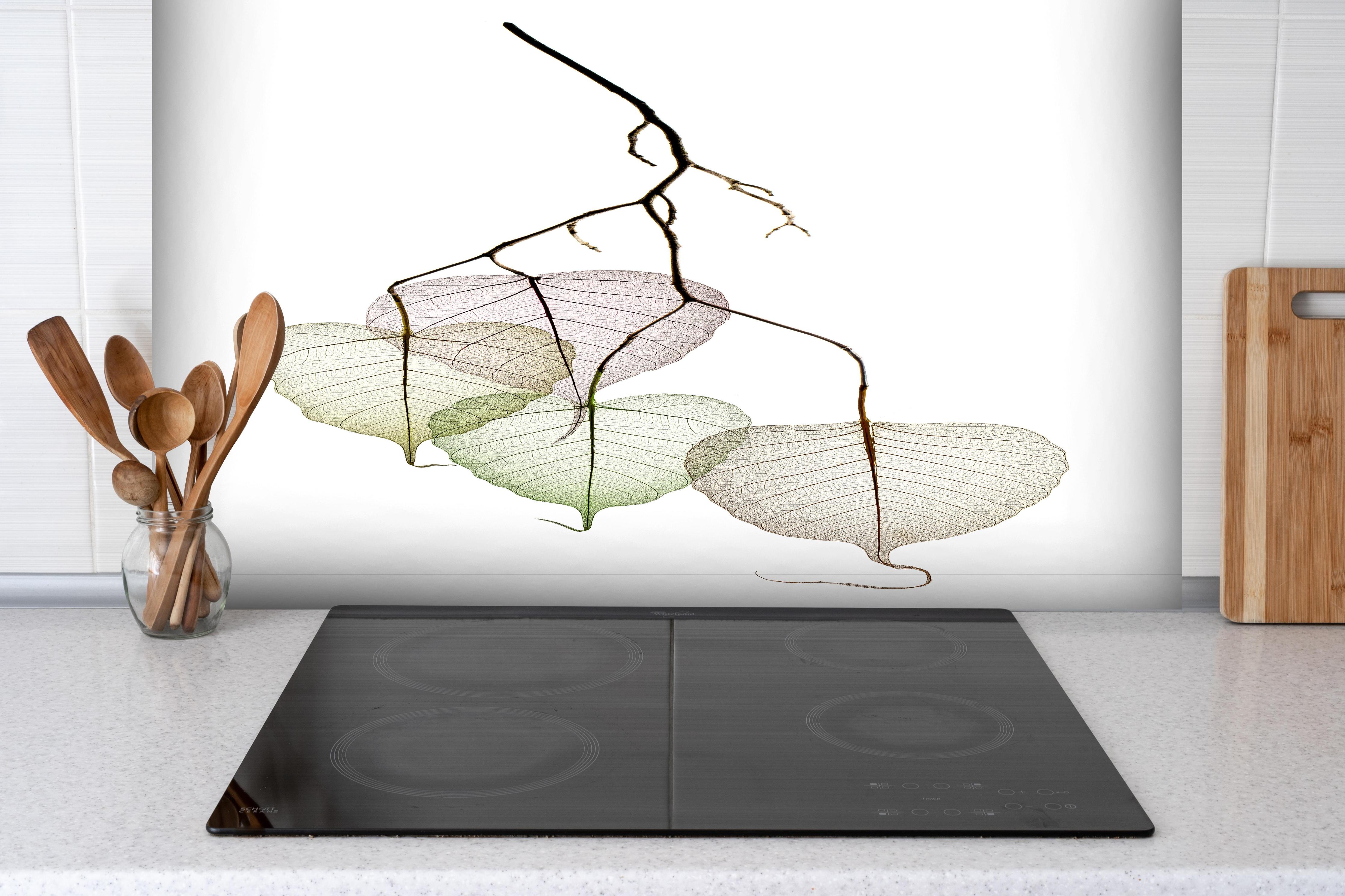 Spritzschutz - Nahaufnahme - Blätterzweige  hinter einem Cerankochfeld zwischen Holz-Kochutensilien
