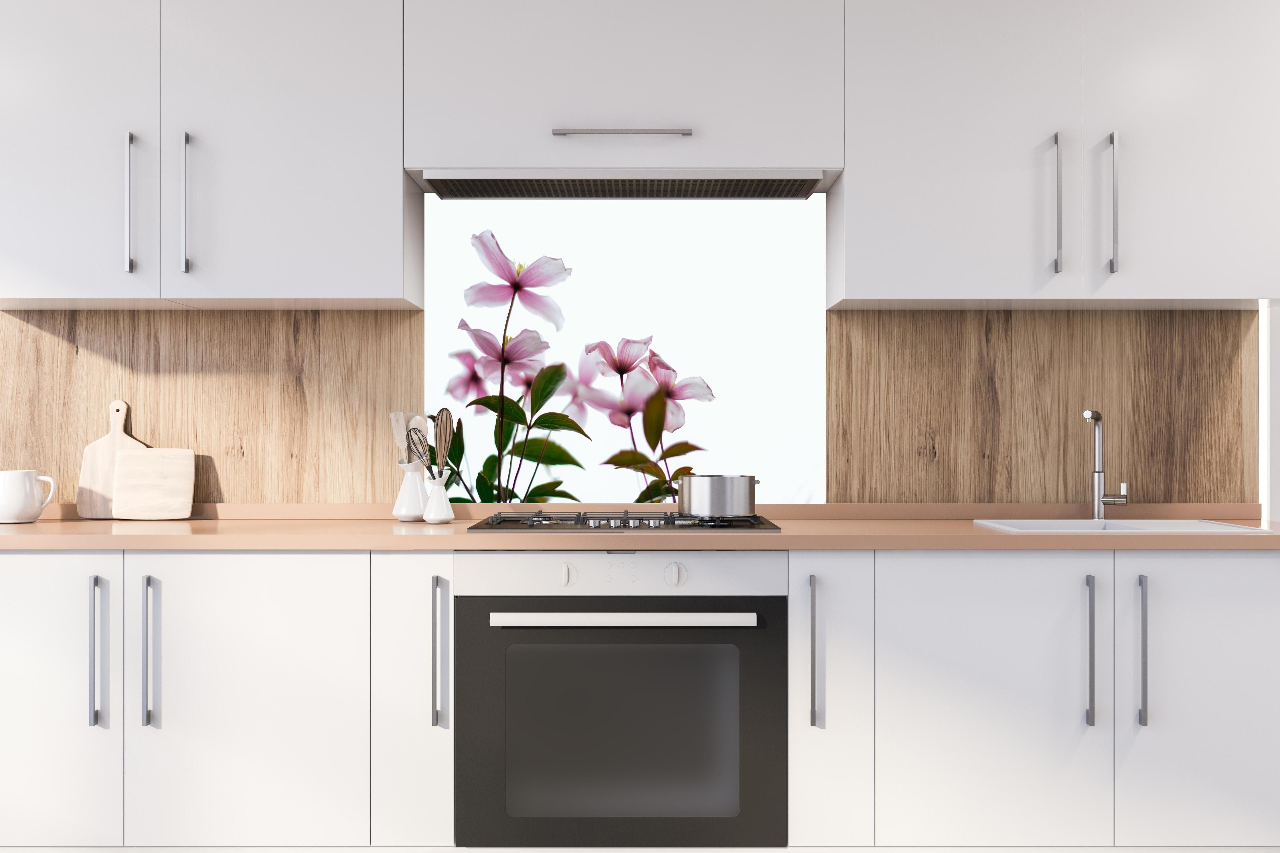 Spritzschutz - Nahaufnahme - Clematis Blüten hinter einem Cerankochfeld zwischen Holz-Kochutensilien
