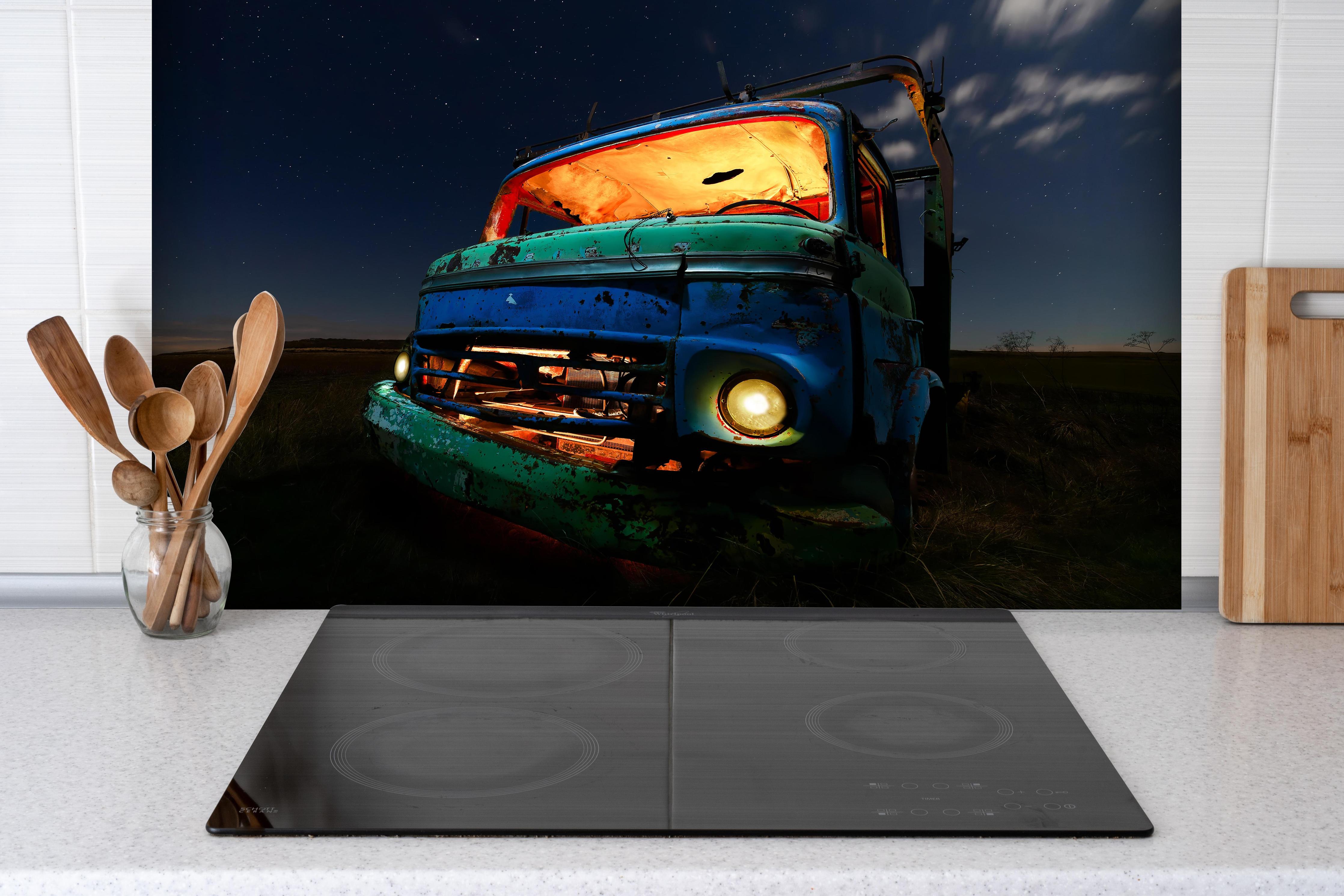 Spritzschutz - Nahaufnahme - Rostiger Lastkraftwagen hinter einem Cerankochfeld zwischen Holz-Kochutensilien
