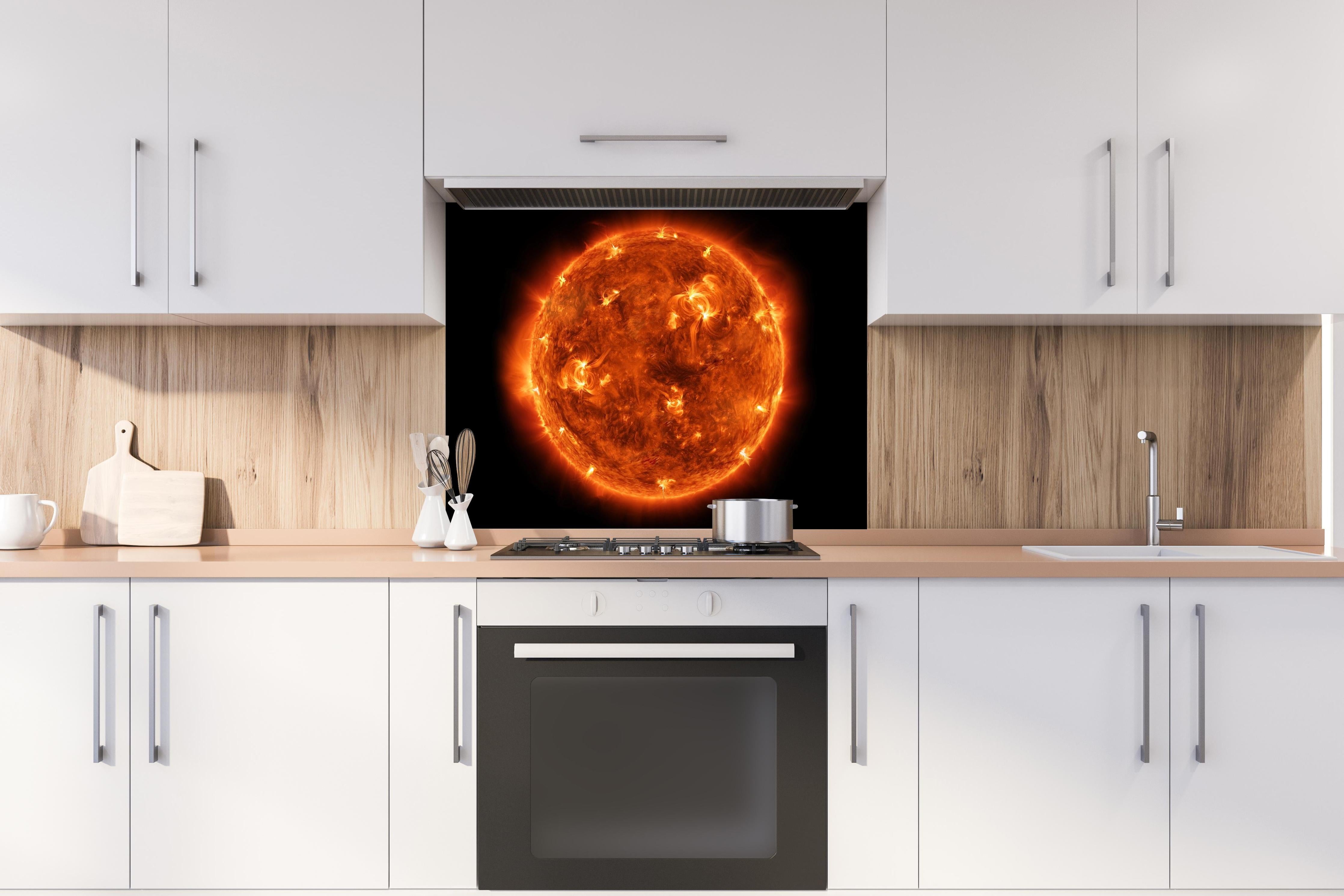 Spritzschutz - Nahaufnahme der Sonne hinter einem Cerankochfeld zwischen Holz-Kochutensilien
