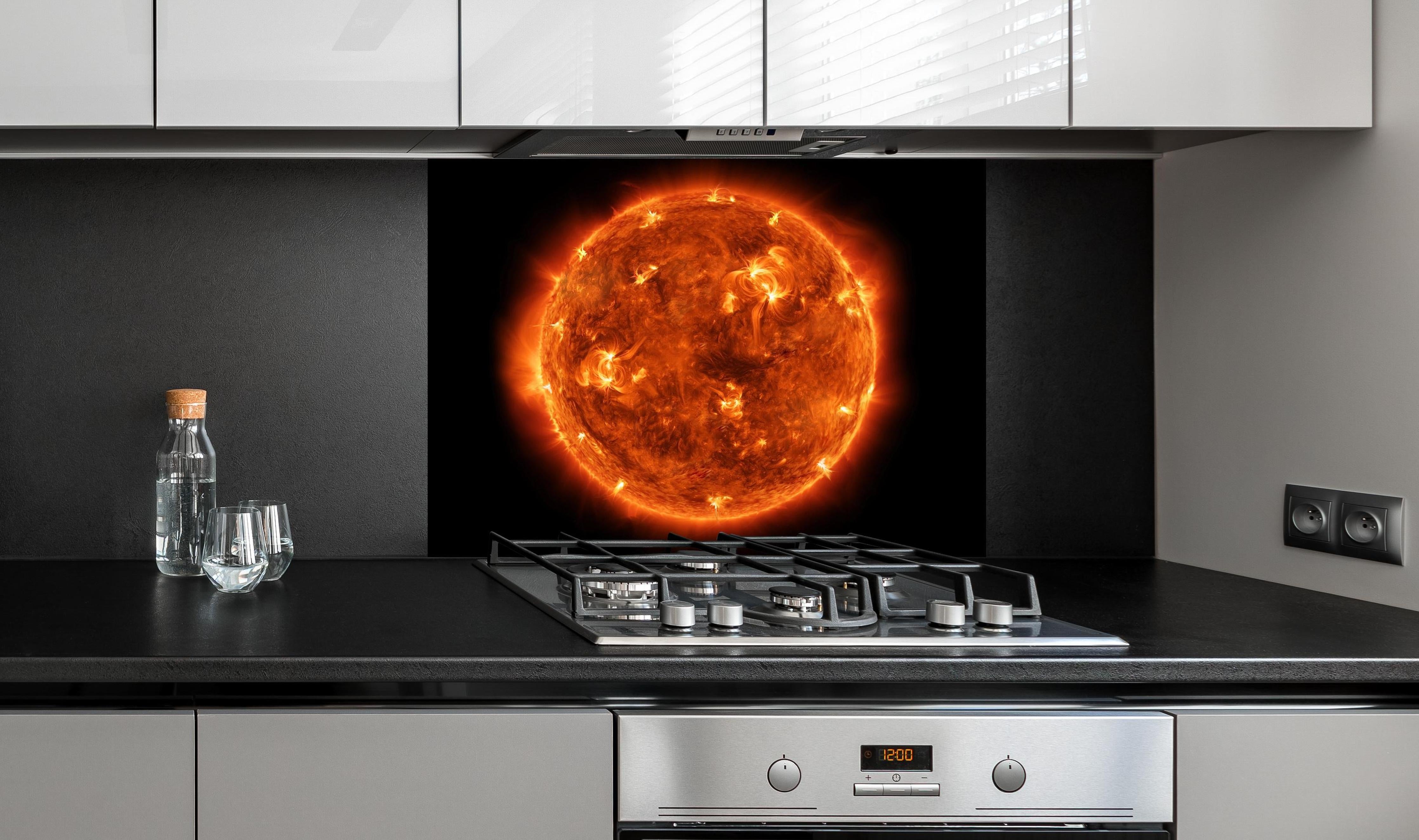 Spritzschutz - Nahaufnahme der Sonne hinter einem Cerankochfeld zwischen Holz-Kochutensilien
