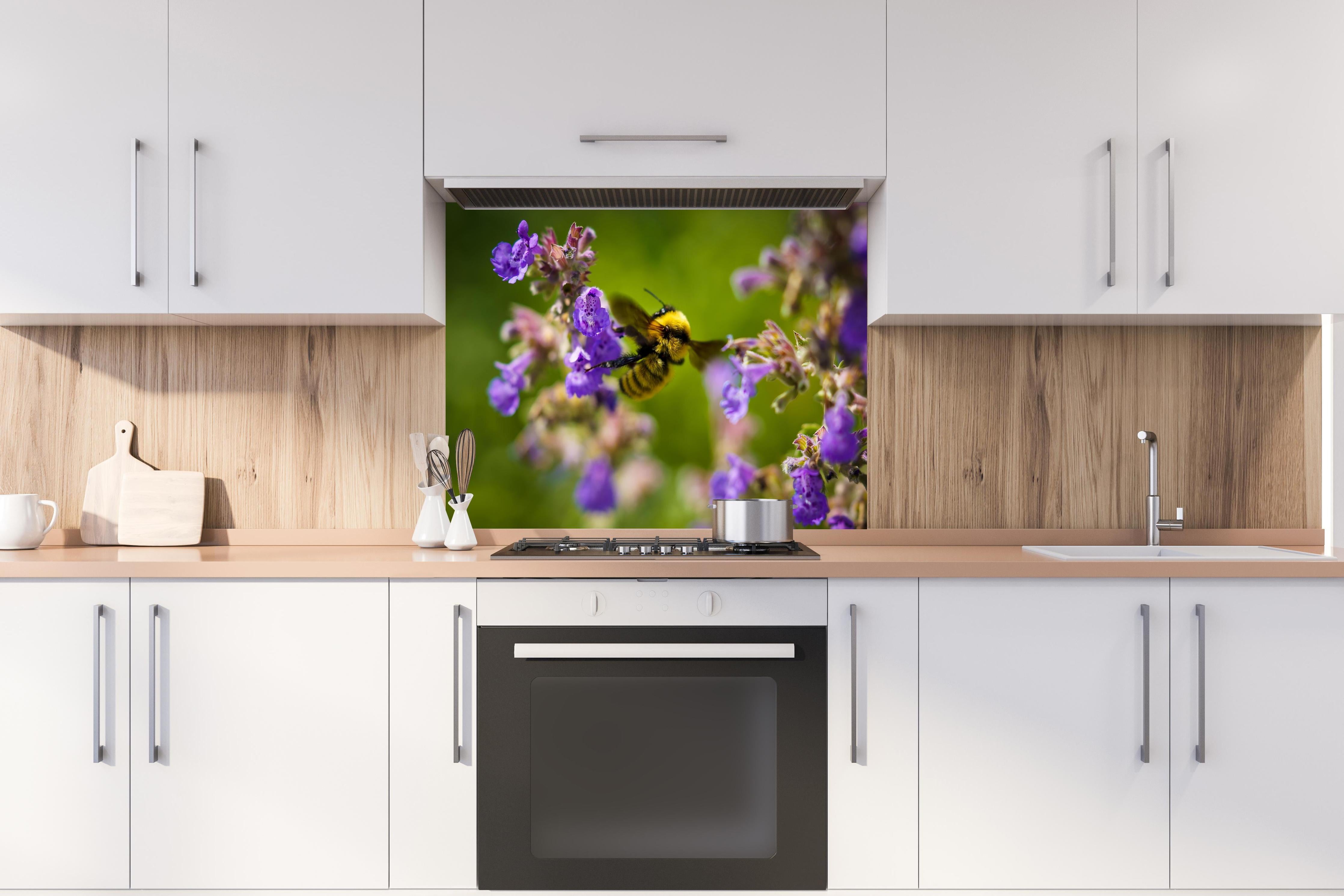 Spritzschutz - Nahaufnahme einer Honigbiene hinter einem Cerankochfeld zwischen Holz-Kochutensilien
