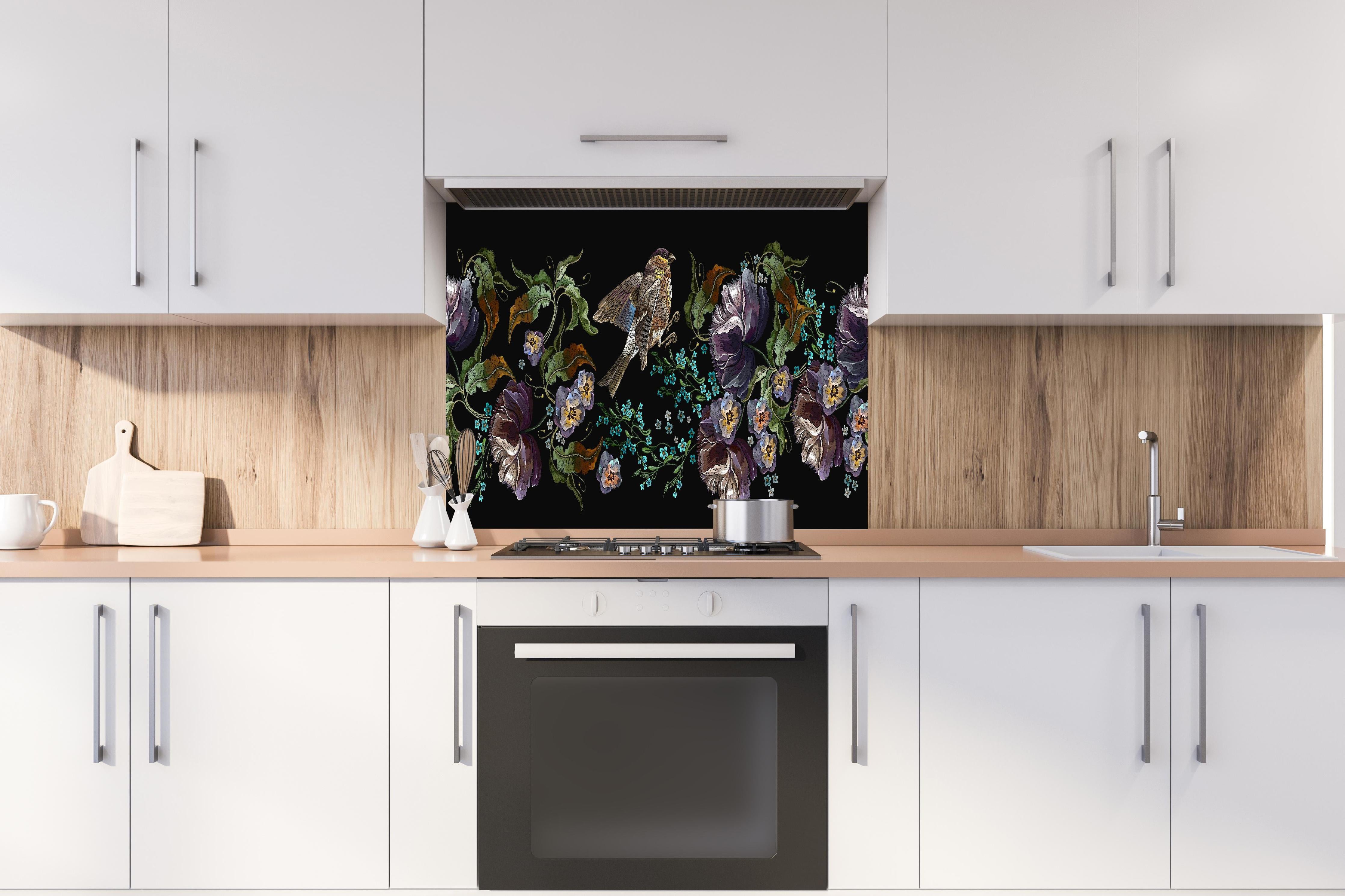 Spritzschutz - Nahtloses Vogel Blumenmuster Stickerei Design hinter einem Cerankochfeld zwischen Holz-Kochutensilien
