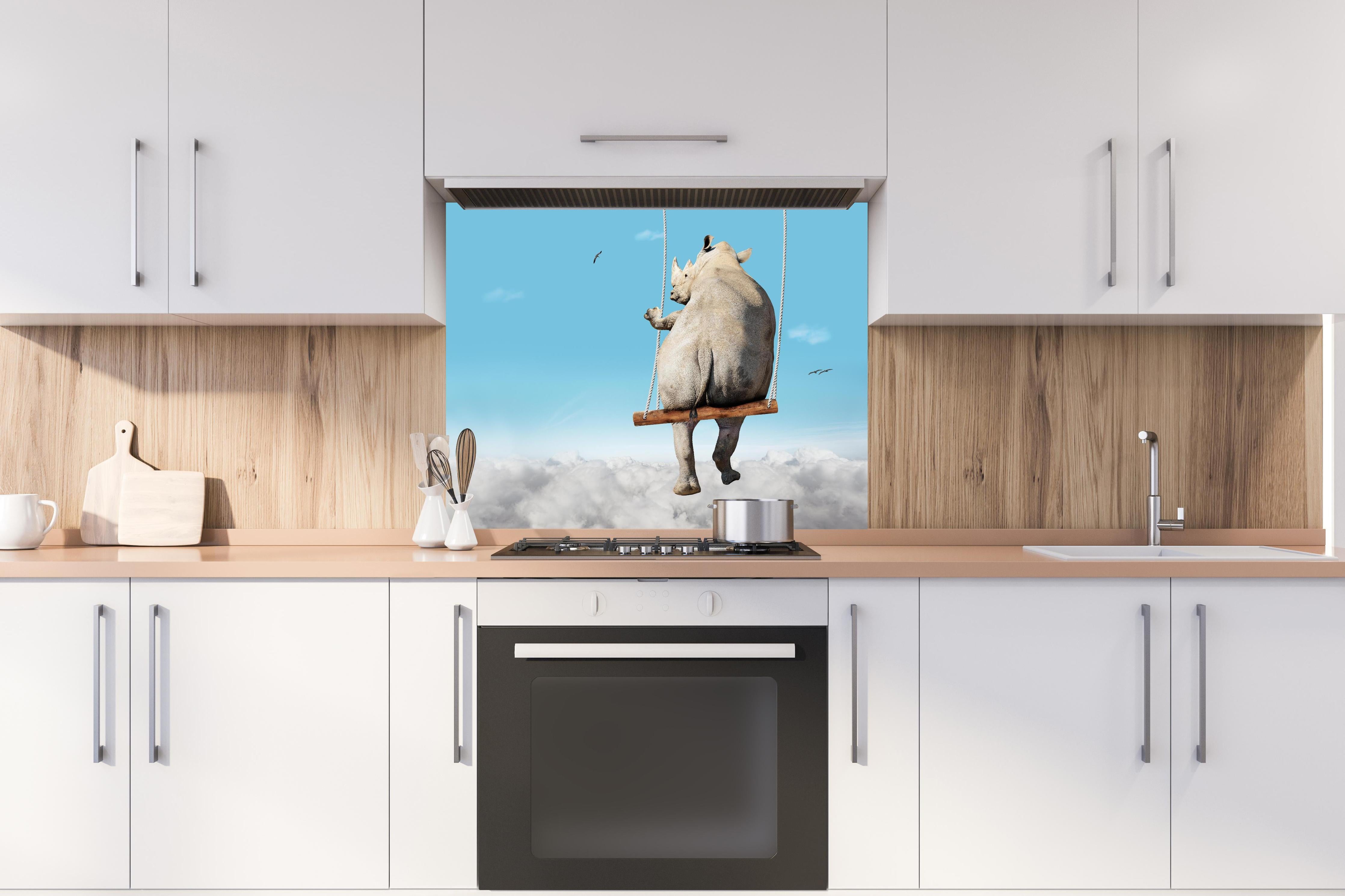 Spritzschutz - Nashorn schaukelt über den Wolken hinter einem Cerankochfeld zwischen Holz-Kochutensilien
