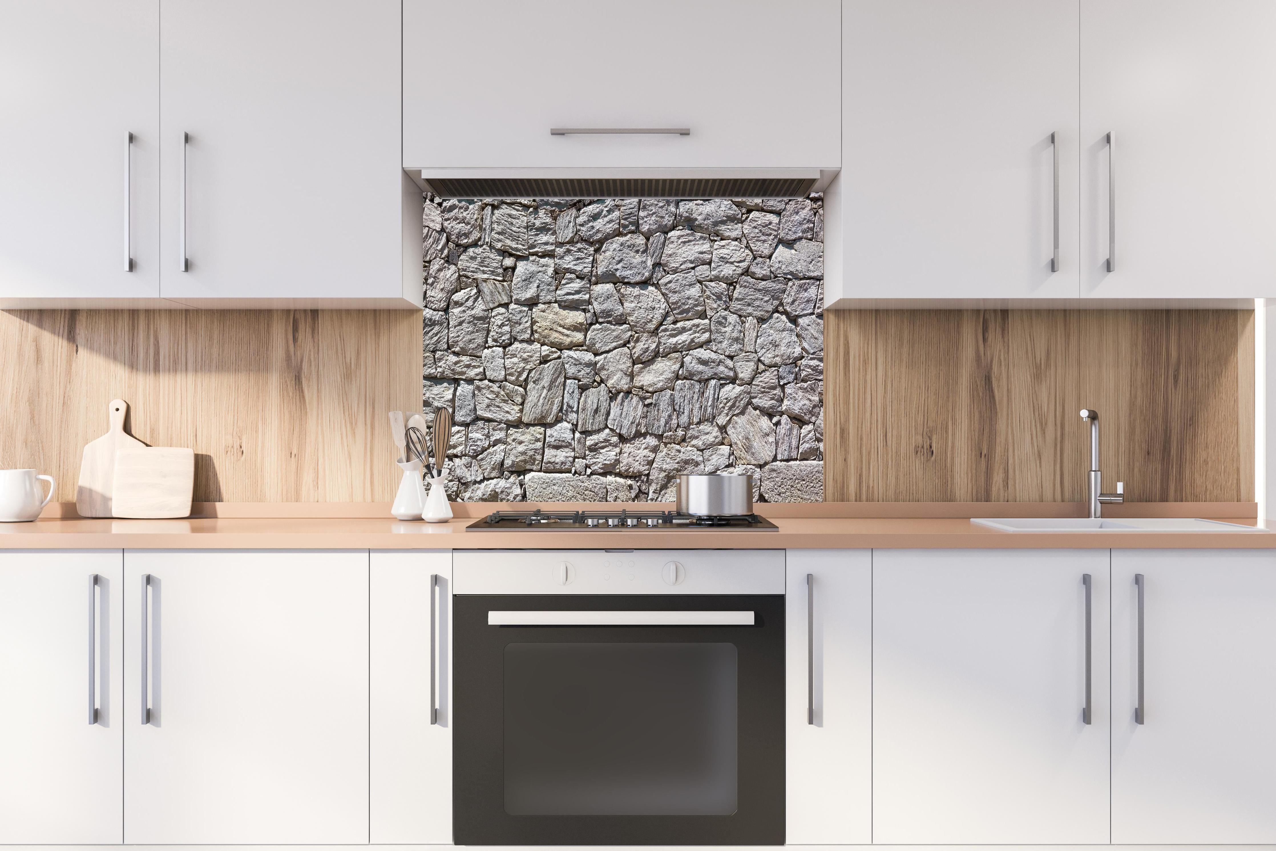 Spritzschutz - Natürliche Steinmauer hinter einem Cerankochfeld zwischen Holz-Kochutensilien
