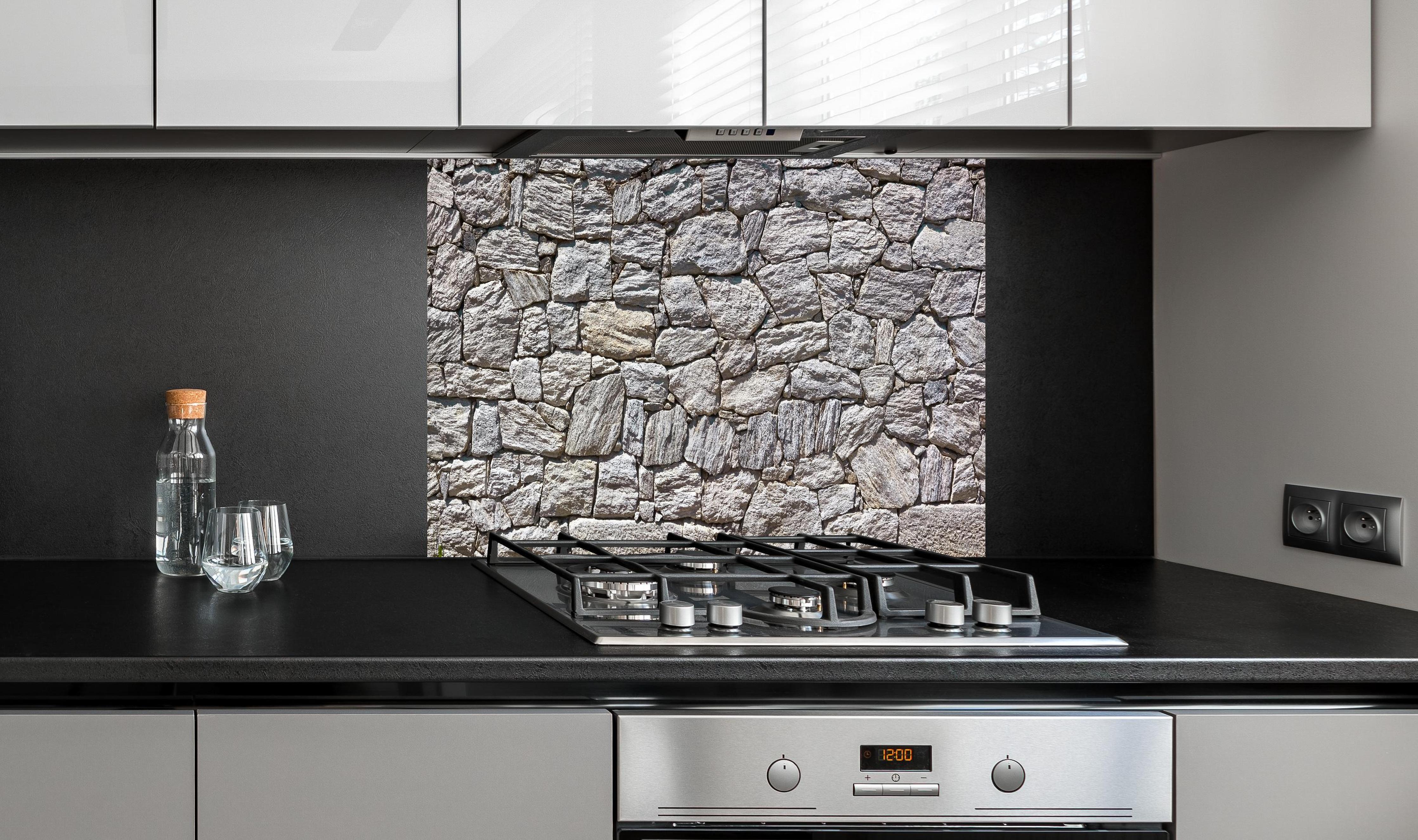 Spritzschutz - Natürliche Steinmauer hinter einem Cerankochfeld zwischen Holz-Kochutensilien

