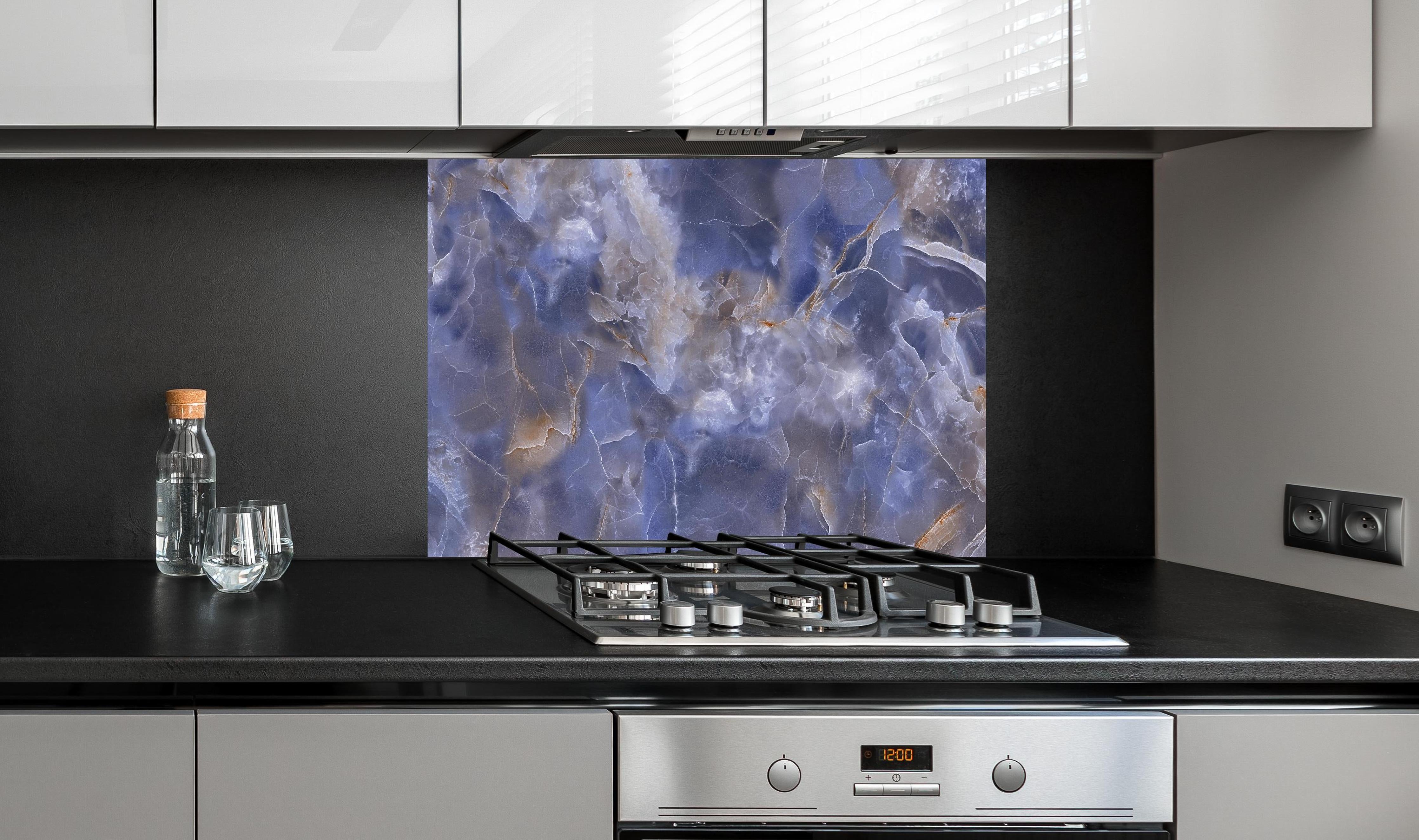 Spritzschutz - Natürlicher Onyx-Marmor hinter einem Cerankochfeld zwischen Holz-Kochutensilien
