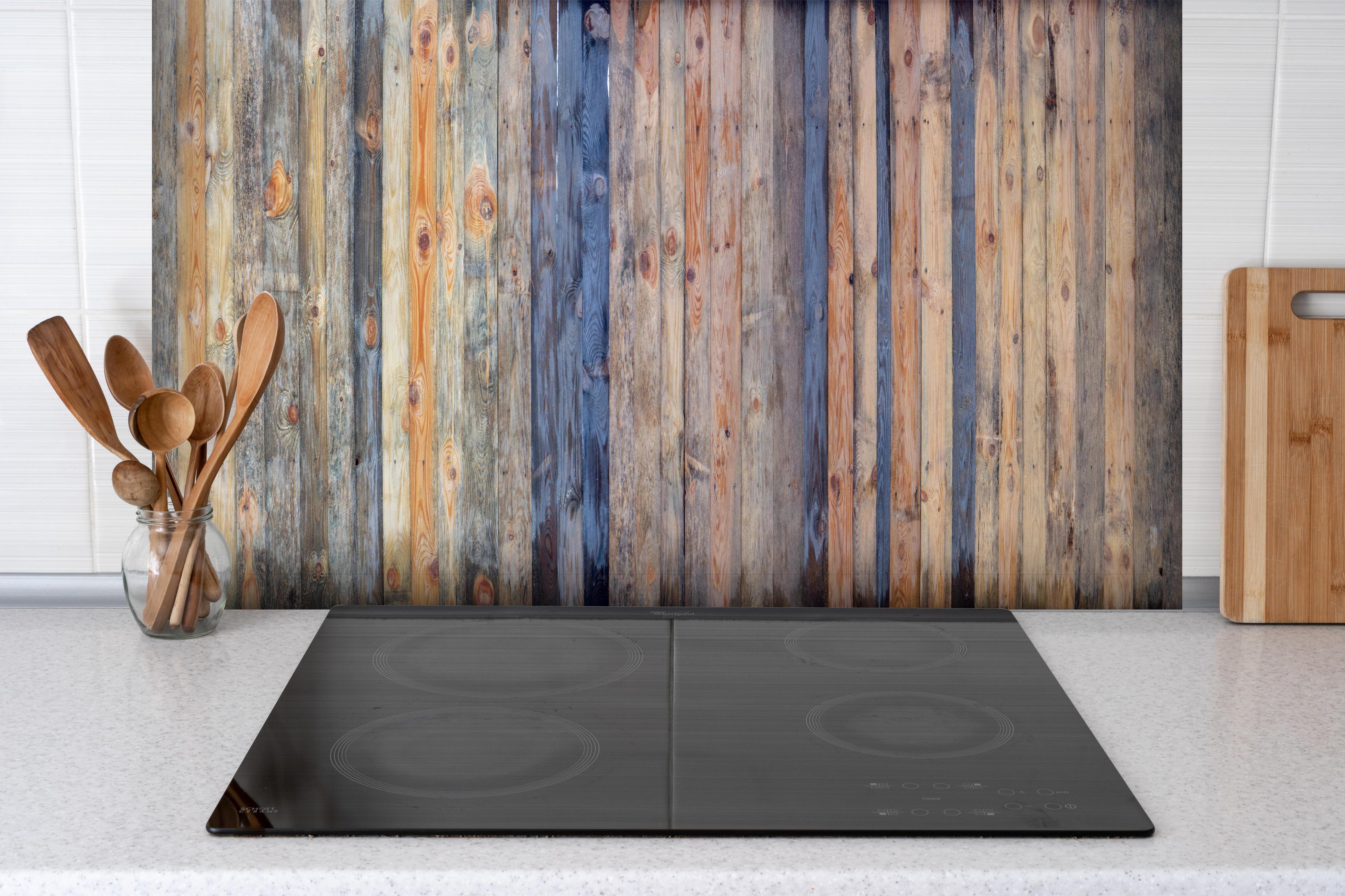 Spritzschutz - Naturholz Textur in Brauntönen hinter einem Cerankochfeld zwischen Holz-Kochutensilien
