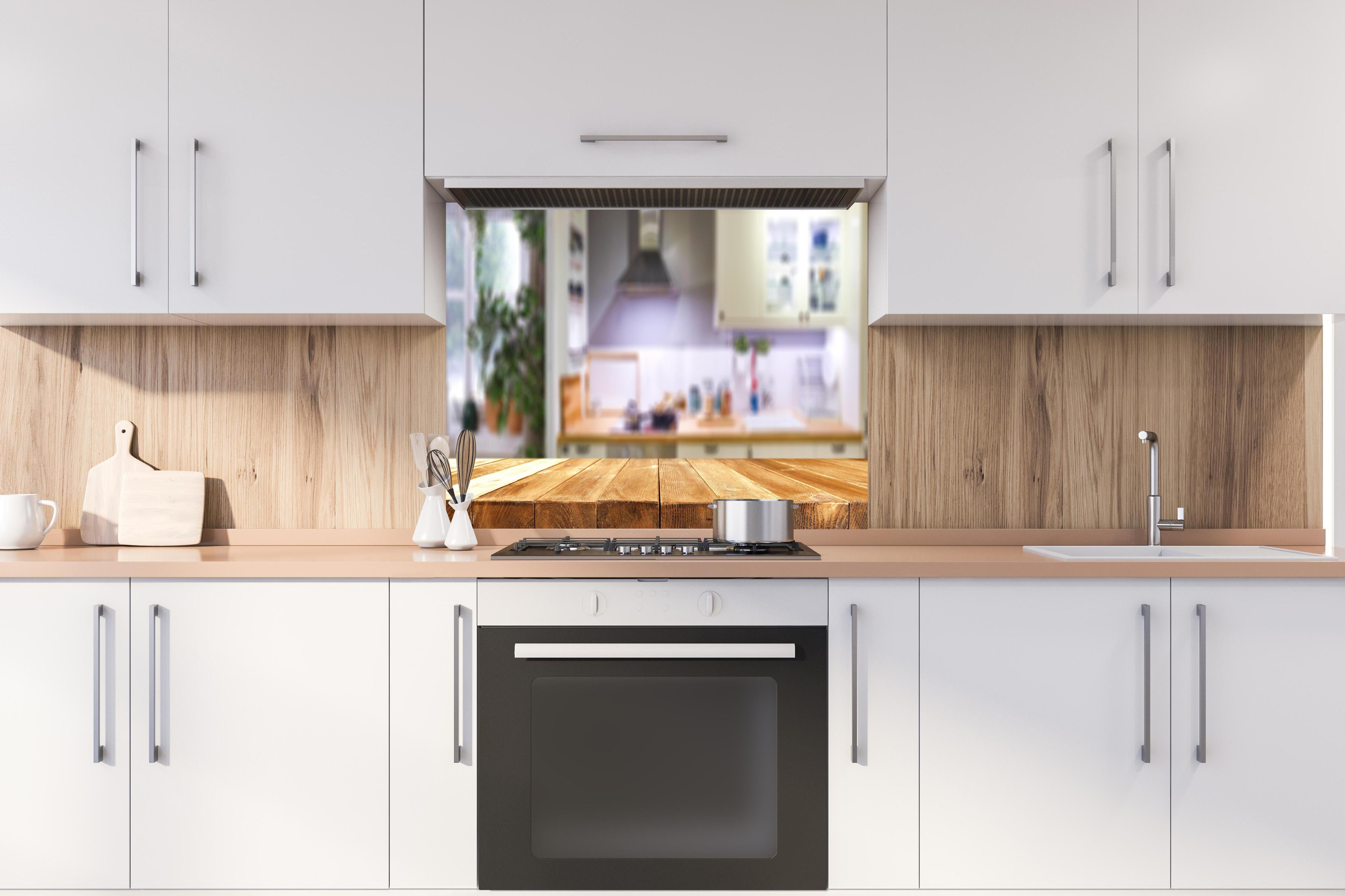 Spritzschutz - Naturholz Tischplatte vor Kücheninterieur hinter einem Cerankochfeld zwischen Holz-Kochutensilien
