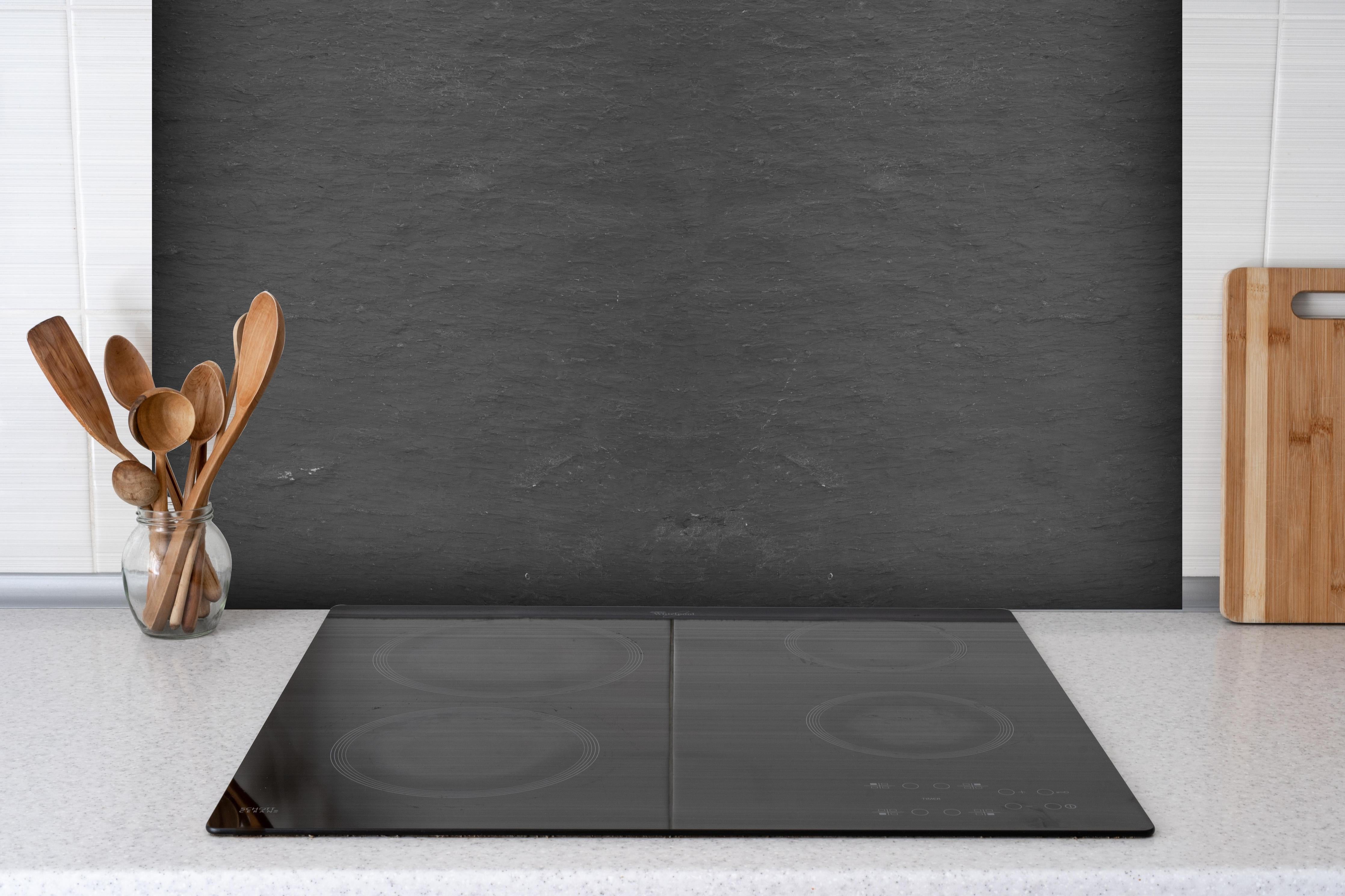 Spritzschutz - Naturstein Schiefer Anthrazit Textur Panorama hinter einem Cerankochfeld zwischen Holz-Kochutensilien
