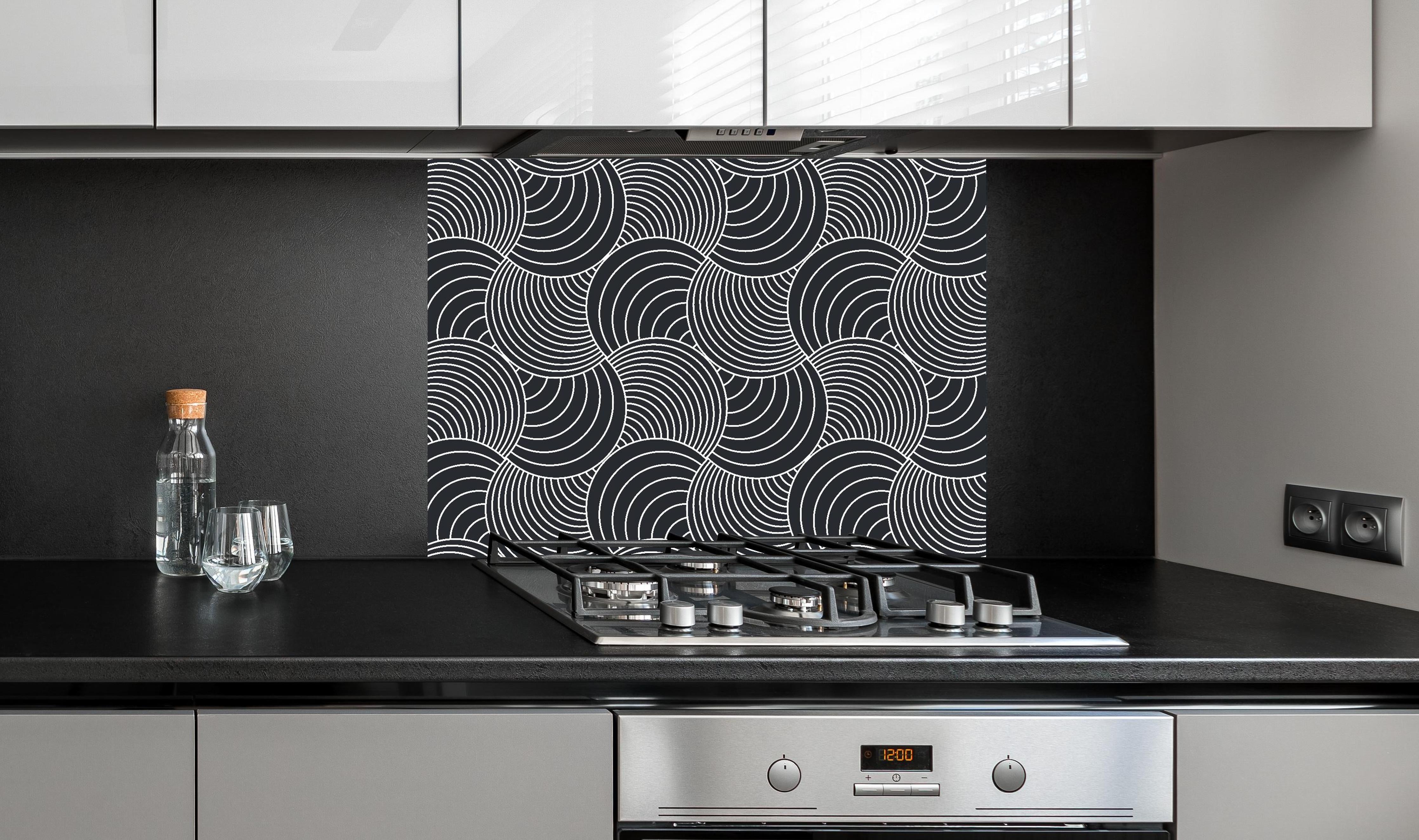 Spritzschutz - Onde Imaginario Carbone hinter einem Cerankochfeld zwischen Holz-Kochutensilien
