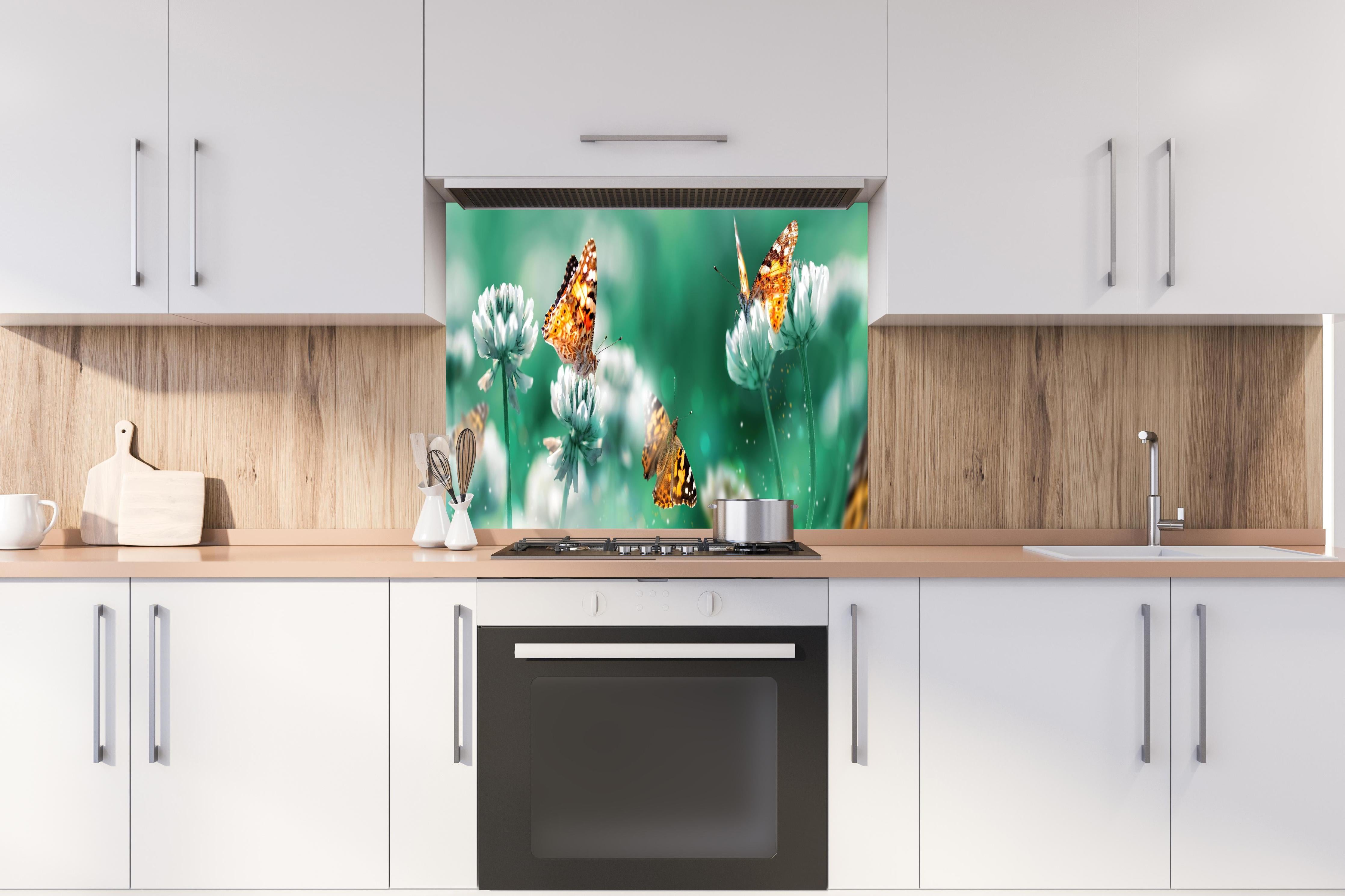 Spritzschutz - Orange Schmetterlinge Sommergarten hinter einem Cerankochfeld zwischen Holz-Kochutensilien
