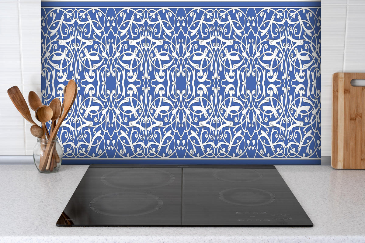 Spritzschutz - Orientalisches Blau-weiß Designmuster hinter einem Cerankochfeld zwischen Holz-Kochutensilien
