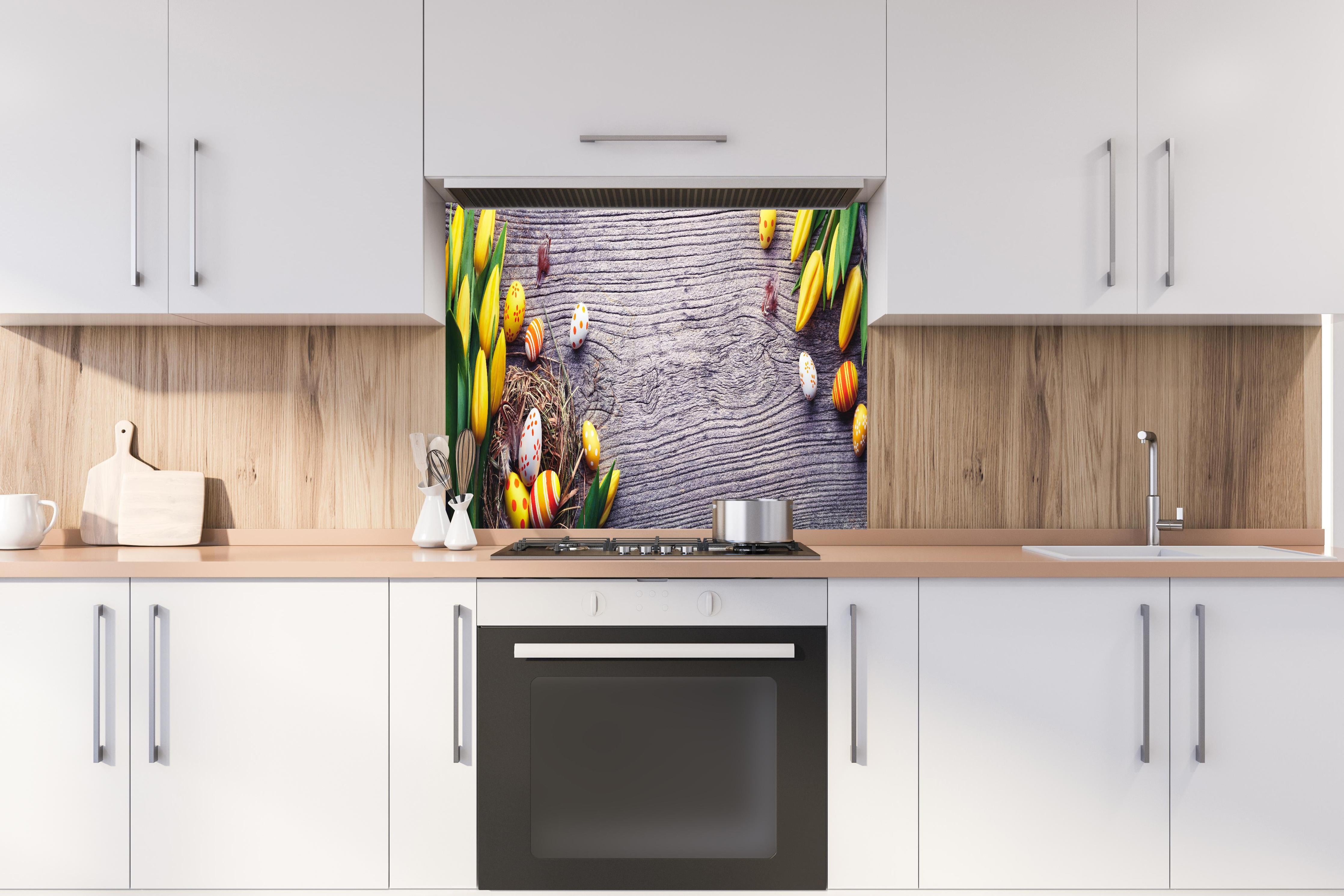 Spritzschutz - Ostereier auf Holztisch hinter einem Cerankochfeld zwischen Holz-Kochutensilien
