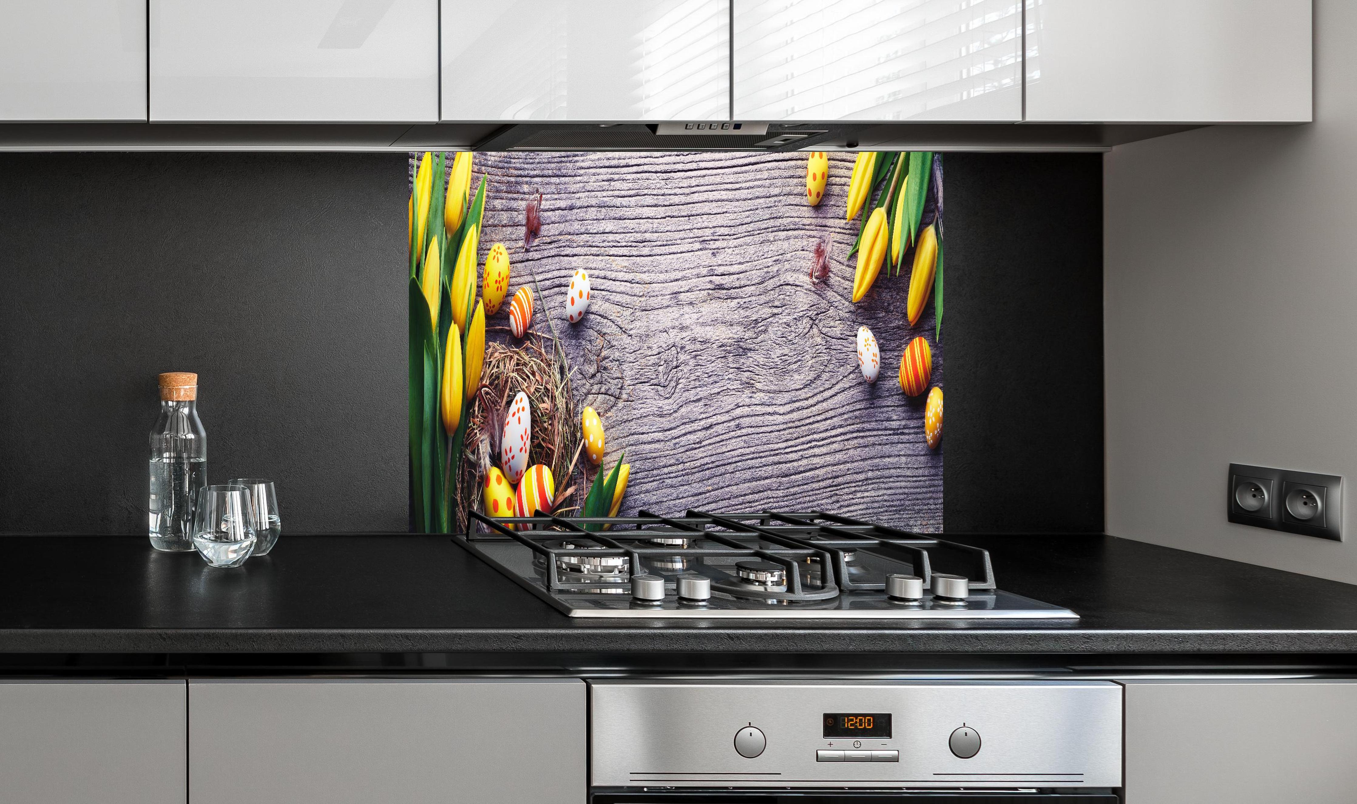 Spritzschutz - Ostereier auf Holztisch hinter einem Cerankochfeld zwischen Holz-Kochutensilien
