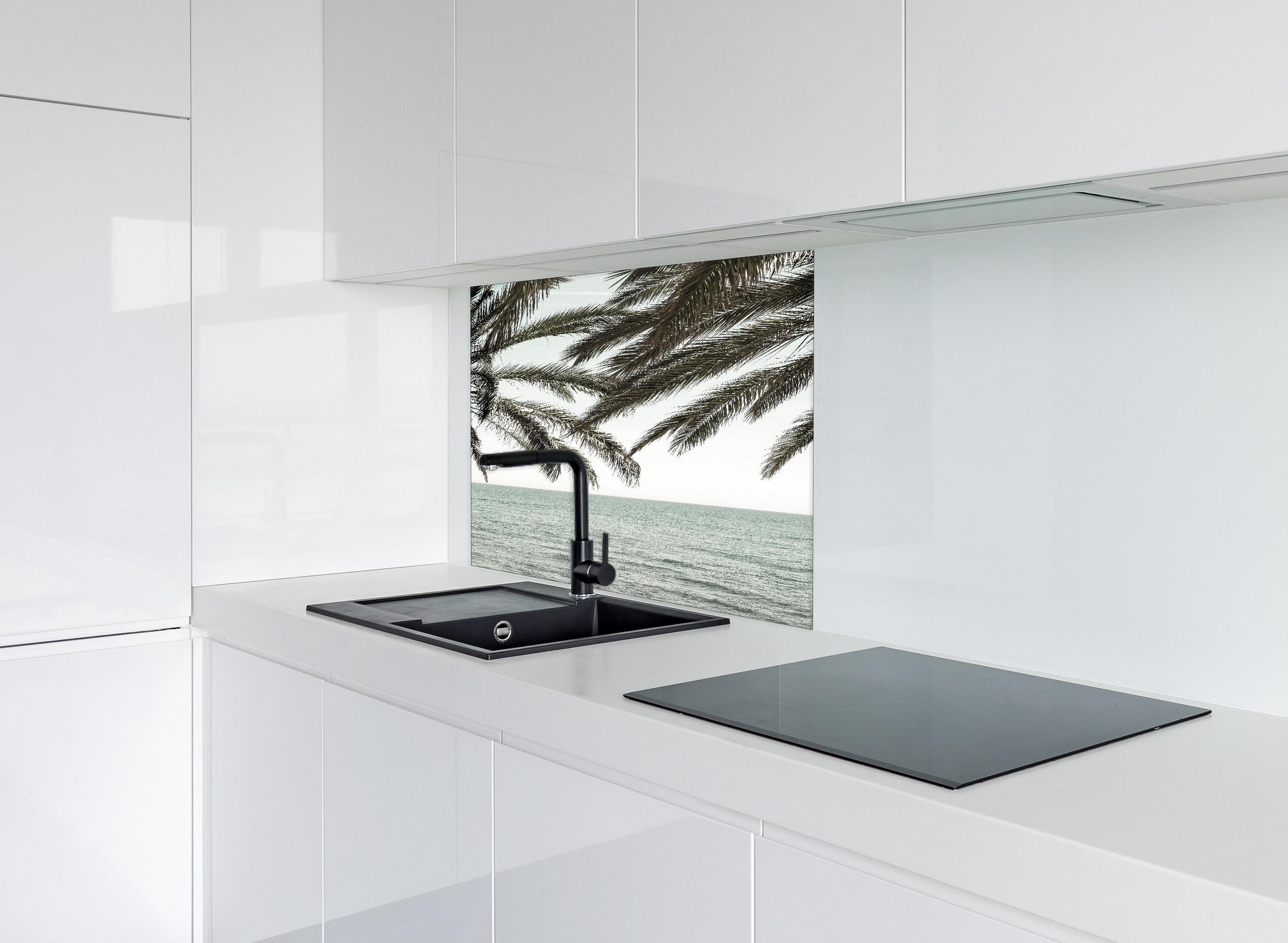 Spritzschutz - Palmen an der Küste  hinter einem Cerankochfeld zwischen Holz-Kochutensilien
