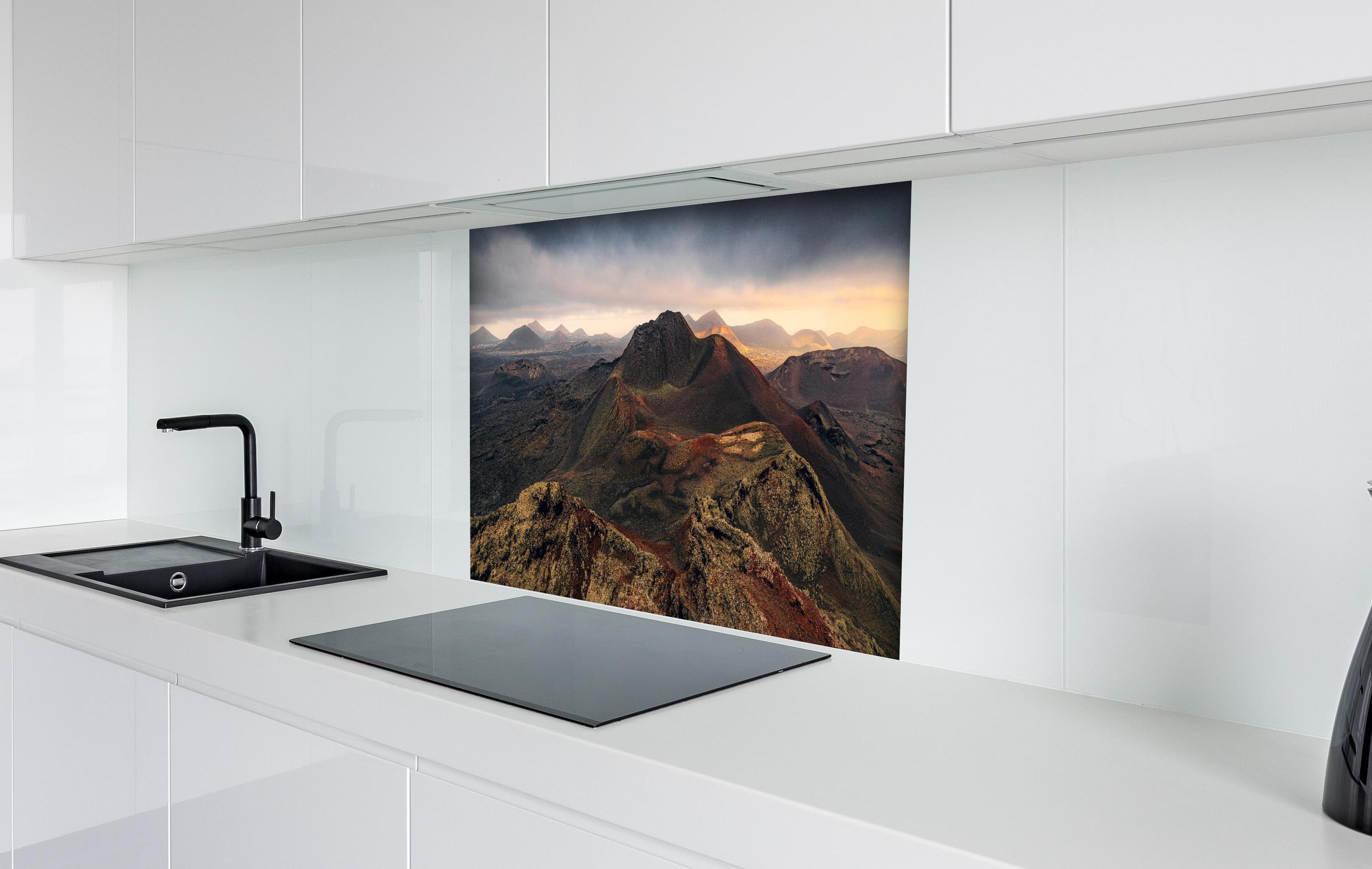 Spritzschutz - Panorama Vulkanberge unter dramatischem Himmel hinter einem Cerankochfeld zwischen Holz-Kochutensilien
