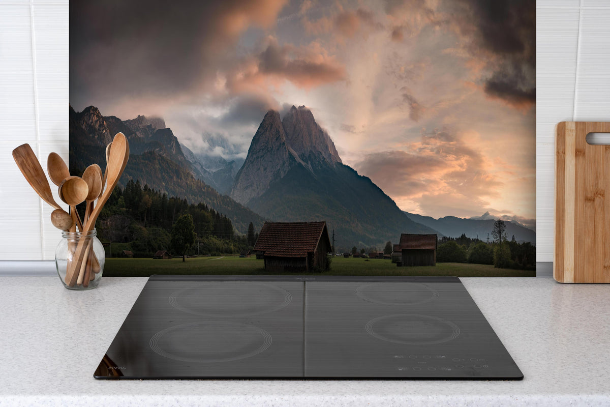 Spritzschutz - Panorama von der wolkenverhangenen Zugspitze hinter einem Cerankochfeld zwischen Holz-Kochutensilien
