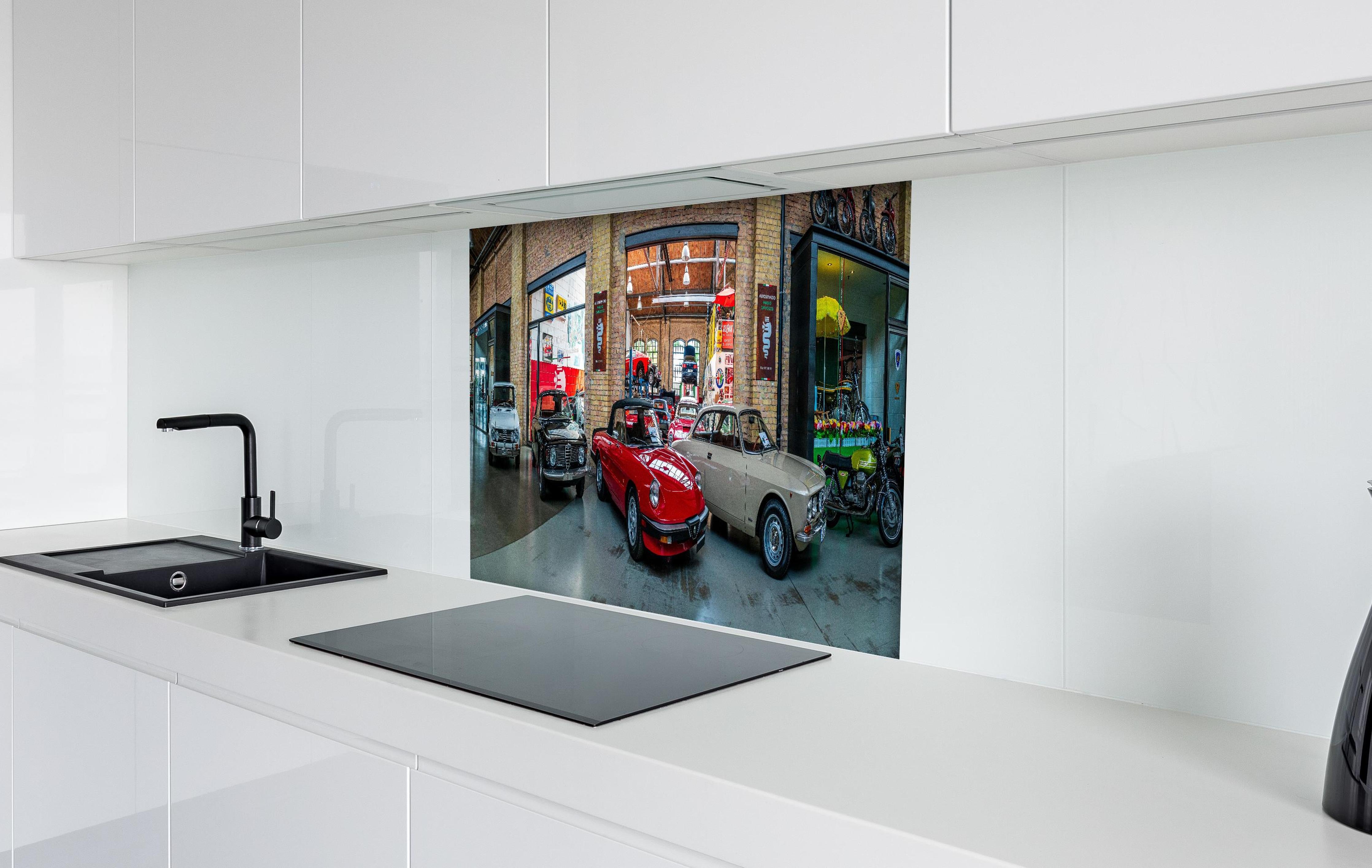 Spritzschutz - Panoramablick auf die Werkstatt der Classic Remise Berlin hinter einem Cerankochfeld zwischen Holz-Kochutensilien
