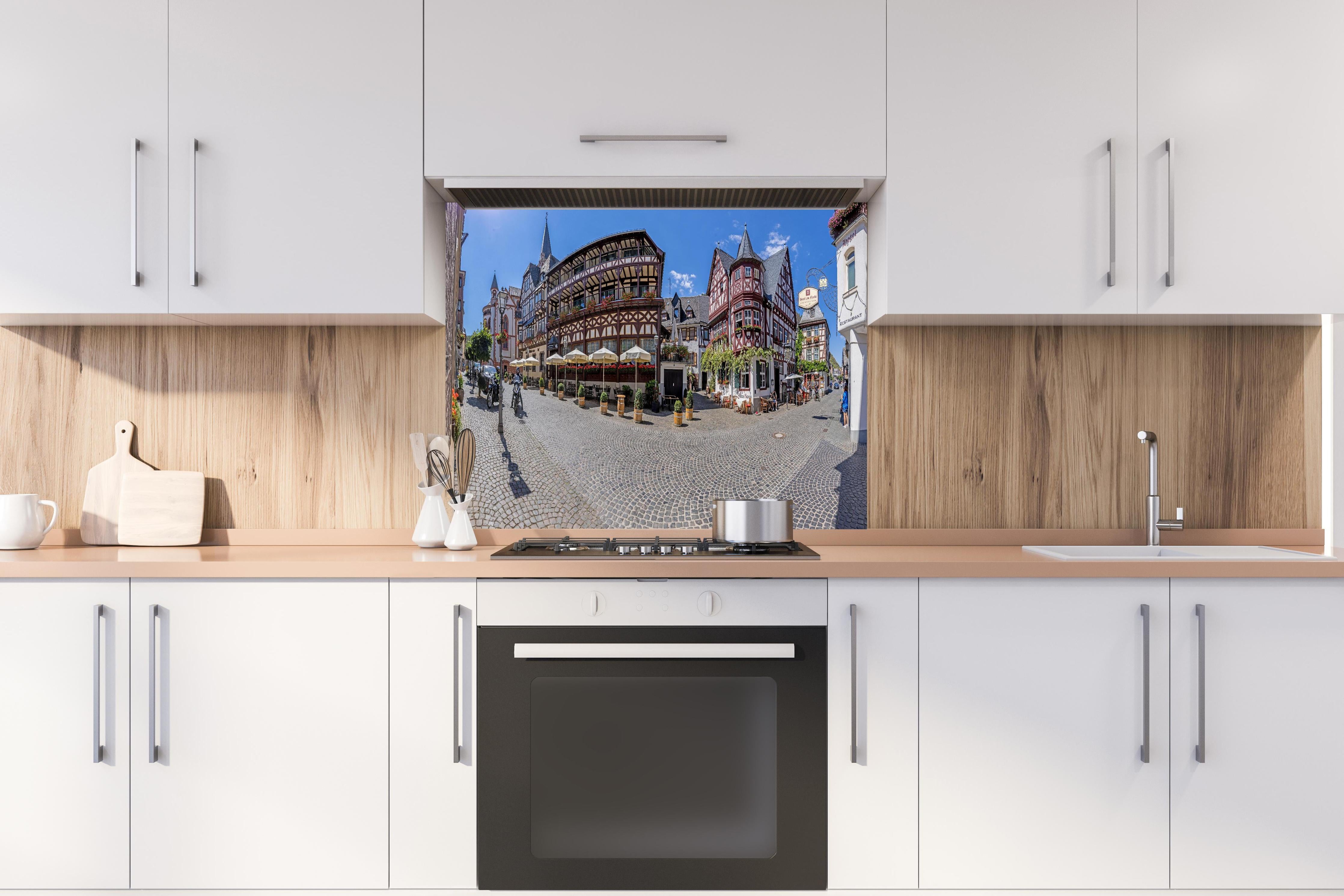 Spritzschutz - Panoramablick über Bacharach hinter einem Cerankochfeld zwischen Holz-Kochutensilien

