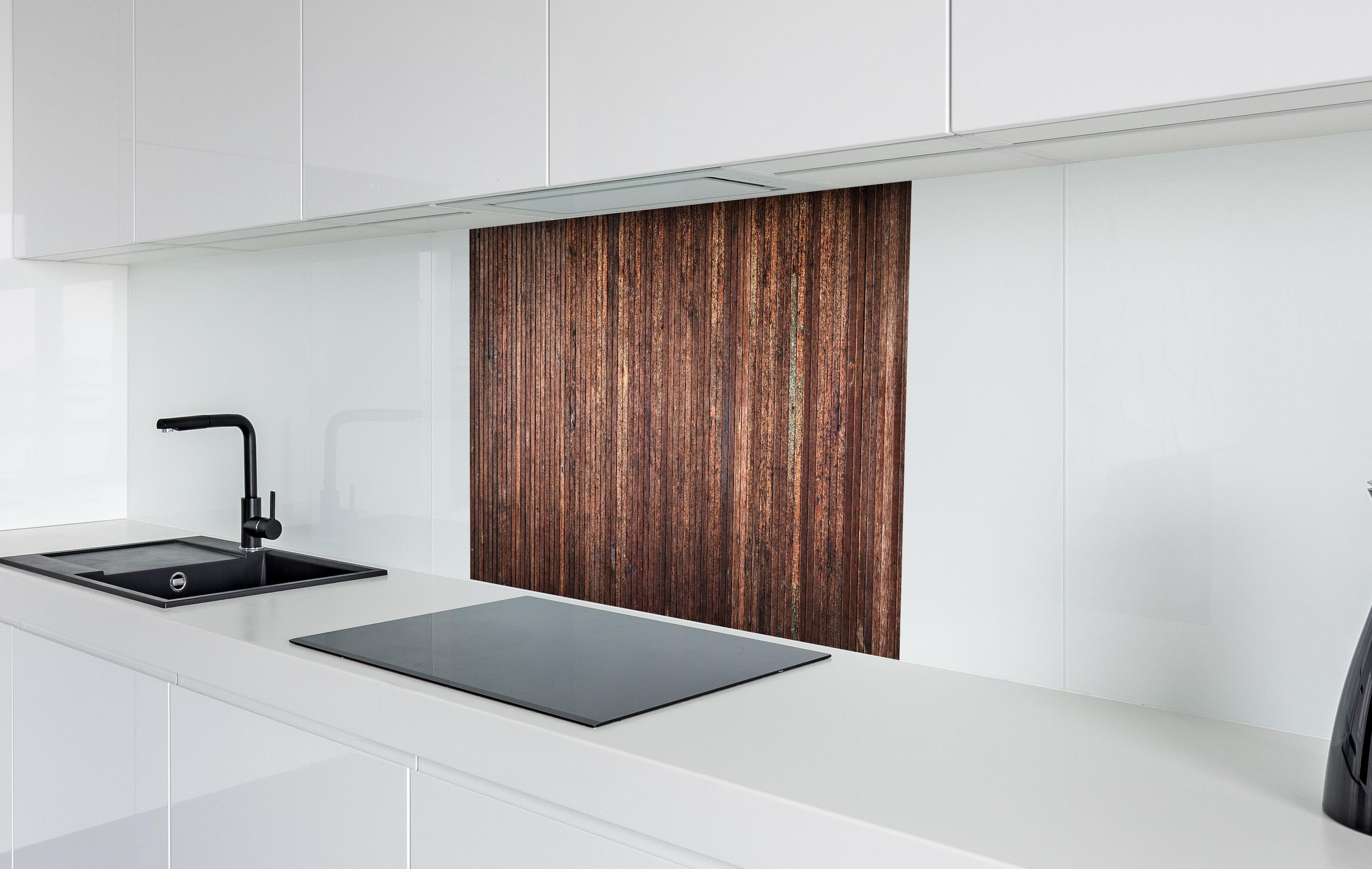 Spritzschutz - Panoramahintergrund aus vertikalen schmalen Holzplatten hinter einem Cerankochfeld zwischen Holz-Kochutensilien
