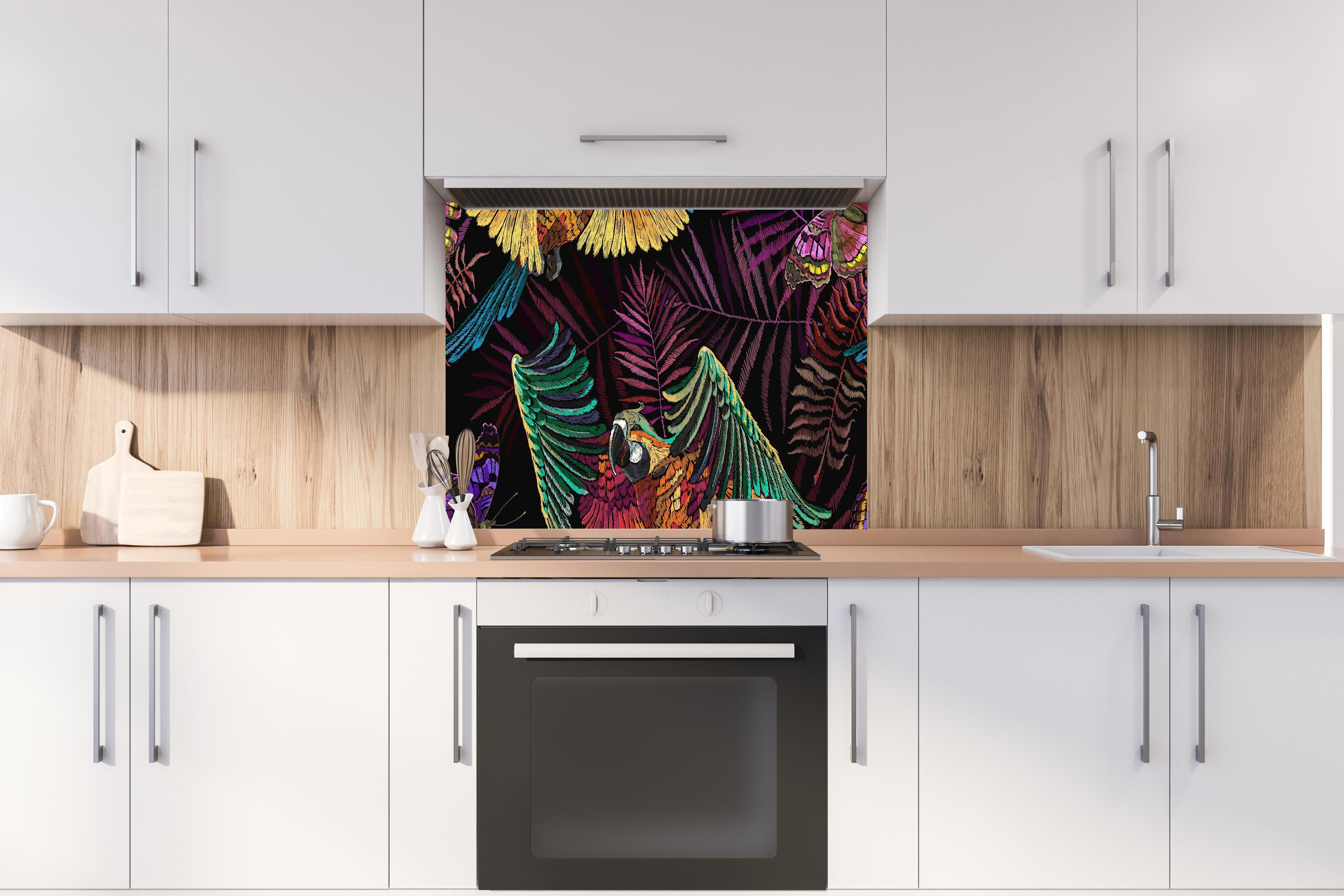 Spritzschutz - Papagaien - Stickmuster hinter einem Cerankochfeld zwischen Holz-Kochutensilien
