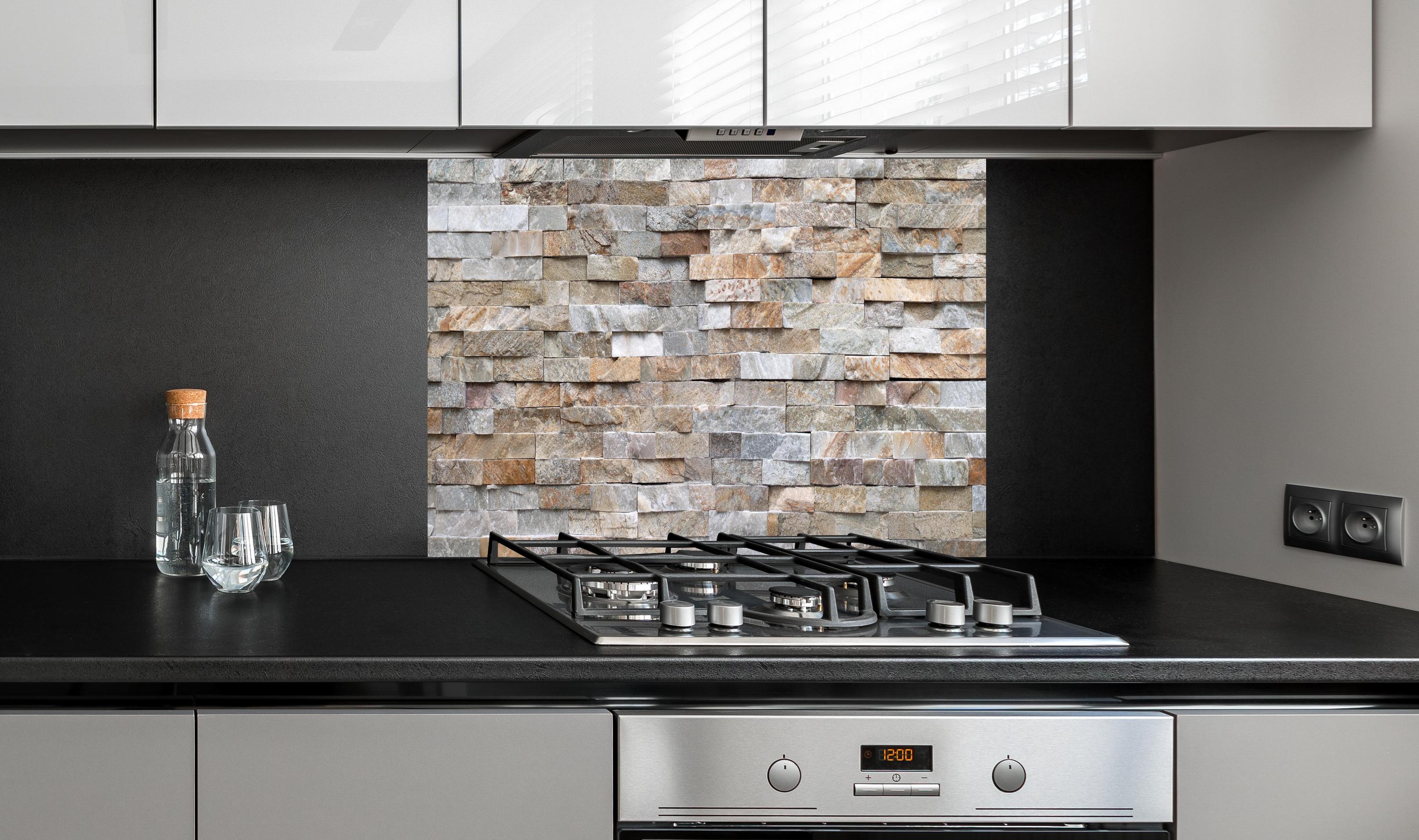 Spritzschutz - Pastellfarbige Steinmauer hinter einem Cerankochfeld zwischen Holz-Kochutensilien
