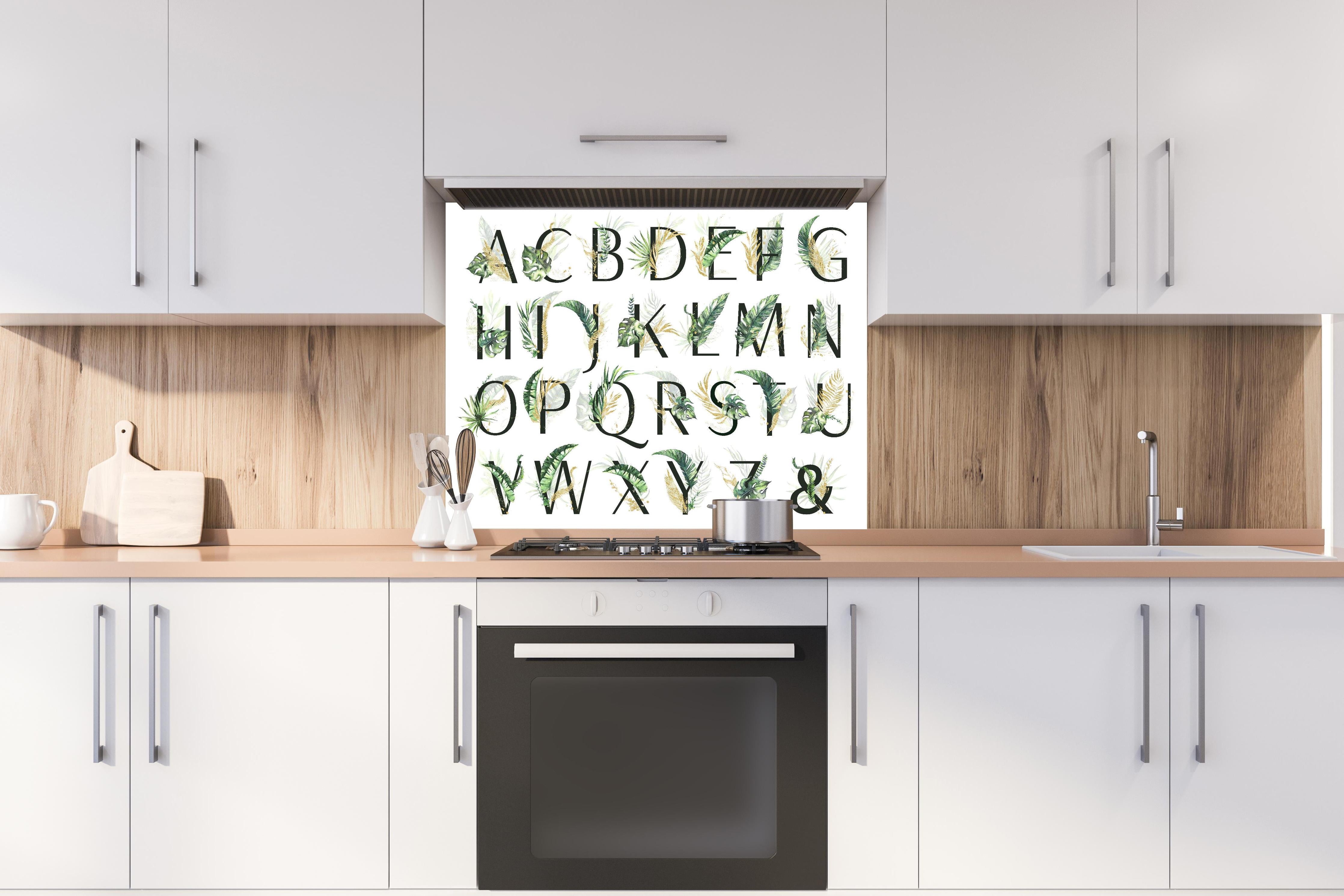 Spritzschutz - Pflanzliche Alphabet Sammlung hinter einem Cerankochfeld zwischen Holz-Kochutensilien
