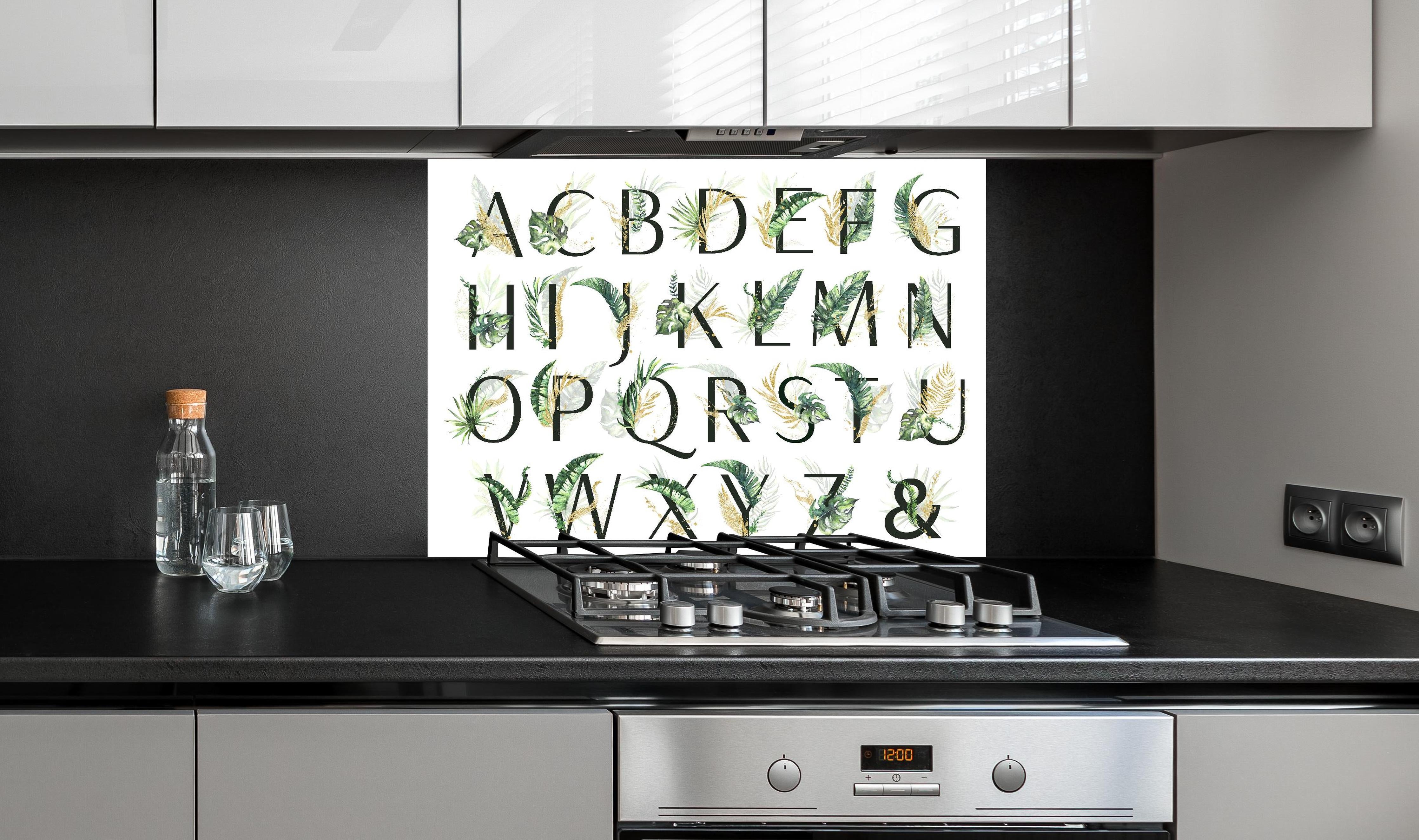 Spritzschutz - Pflanzliche Alphabet Sammlung hinter einem Cerankochfeld zwischen Holz-Kochutensilien
