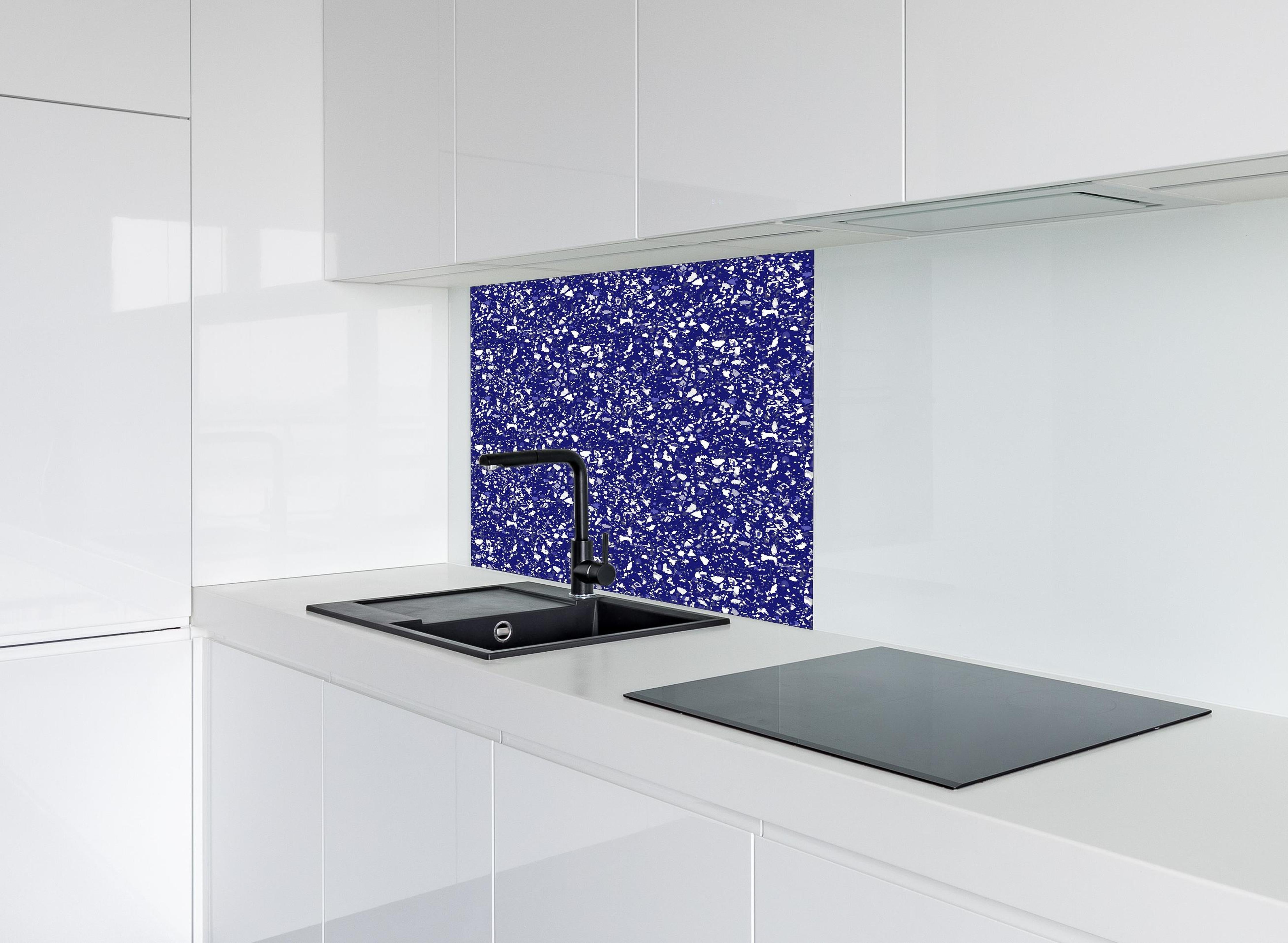 Spritzschutz - Pietre Terrazzo Zaffiro hinter einem Cerankochfeld zwischen Holz-Kochutensilien
