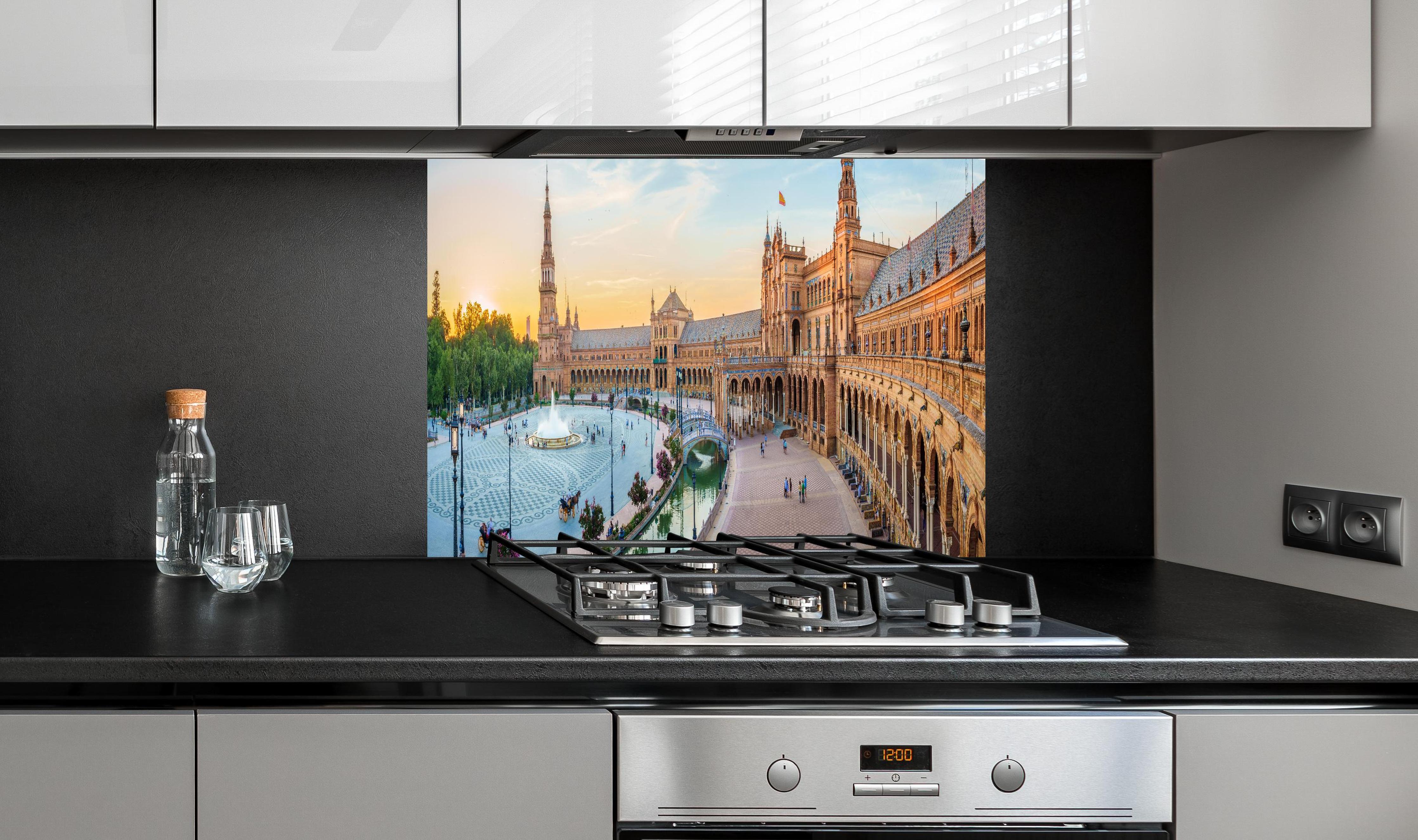 Spritzschutz - Plaza Espana Panorama in Abenddämmerung hinter einem Cerankochfeld zwischen Holz-Kochutensilien
