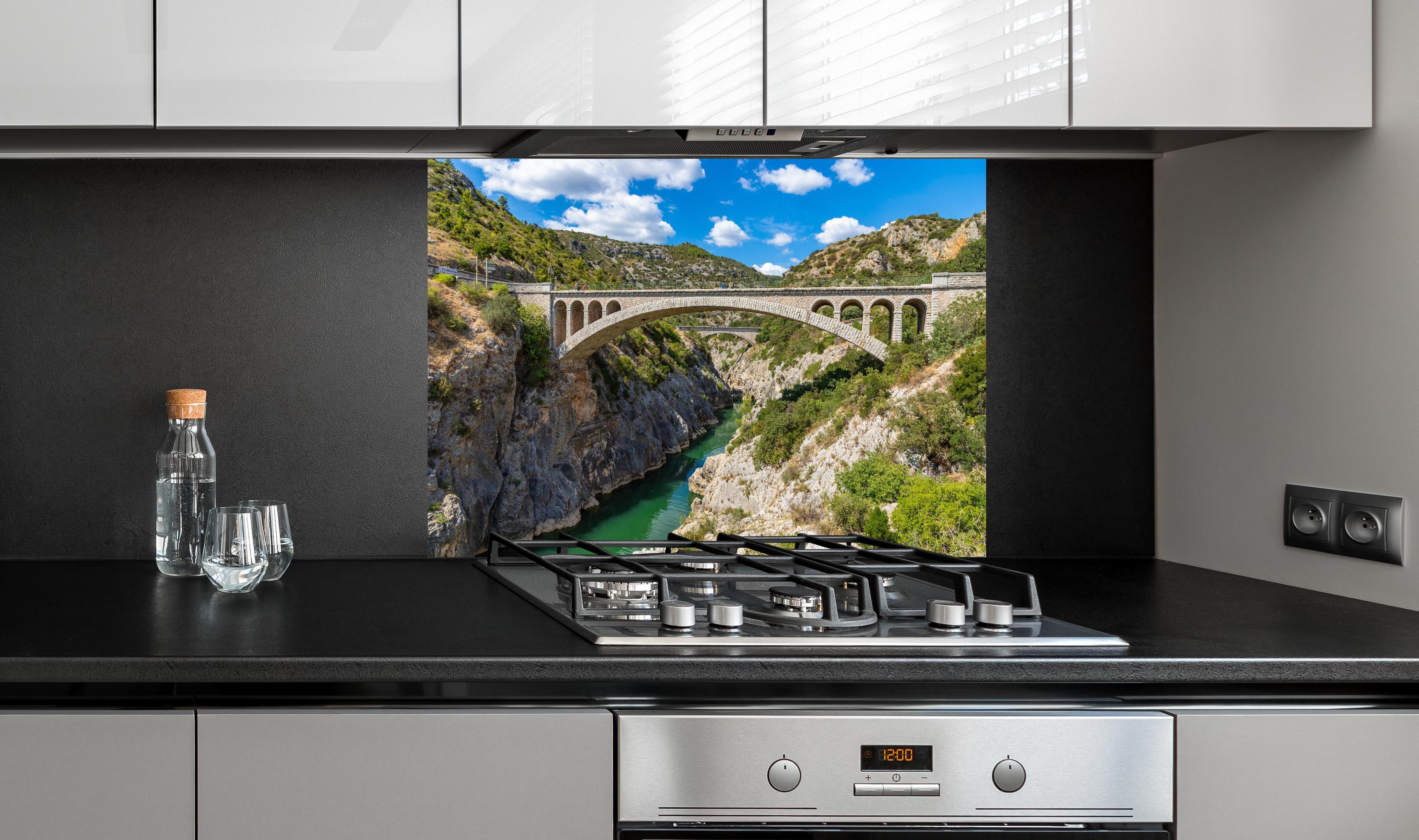 Spritzschutz - Pont du Diable - Frankreich  hinter einem Cerankochfeld zwischen Holz-Kochutensilien
