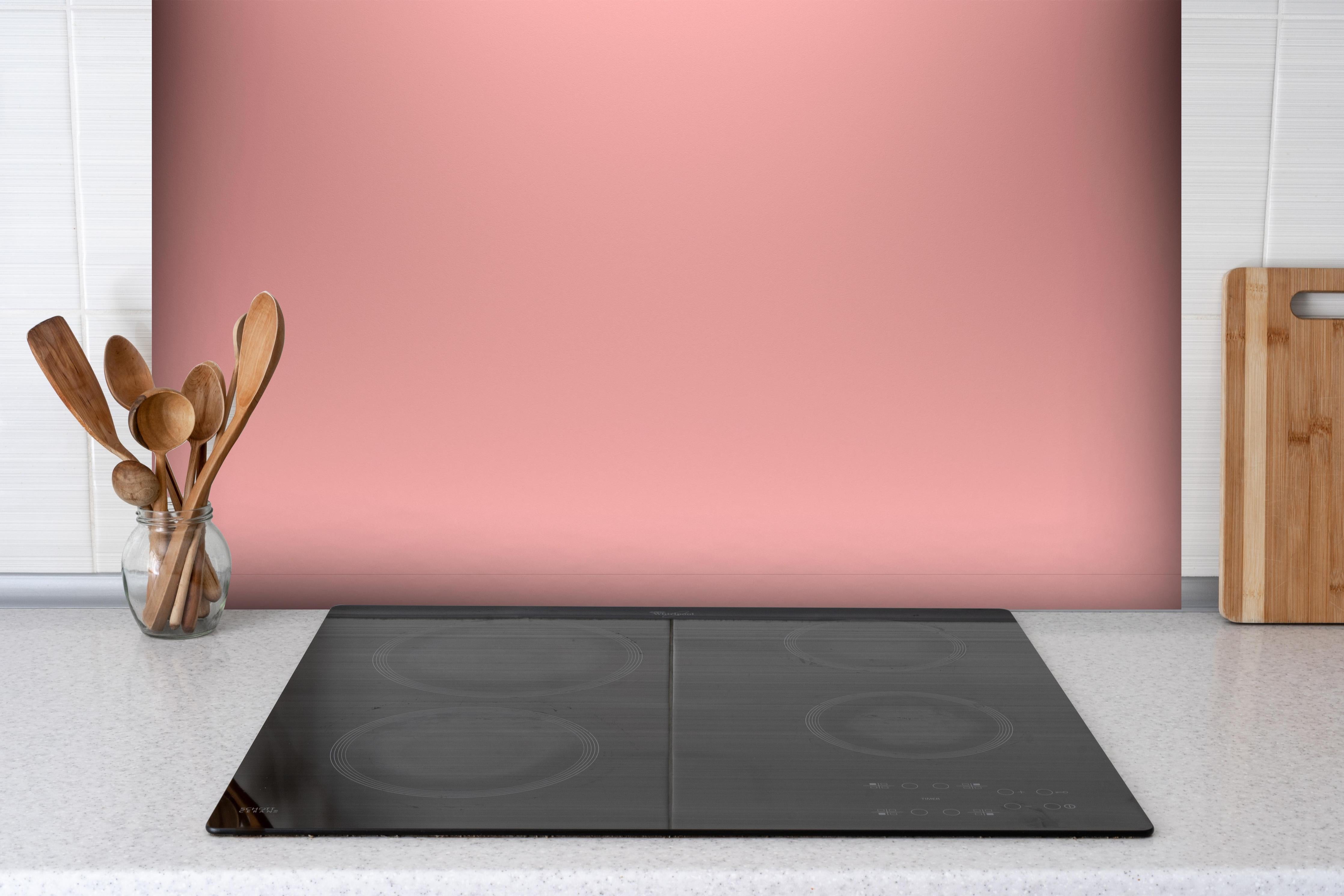 Spritzschutz - Rosa Oberfläche - Papiertextur hinter einem Cerankochfeld zwischen Holz-Kochutensilien
