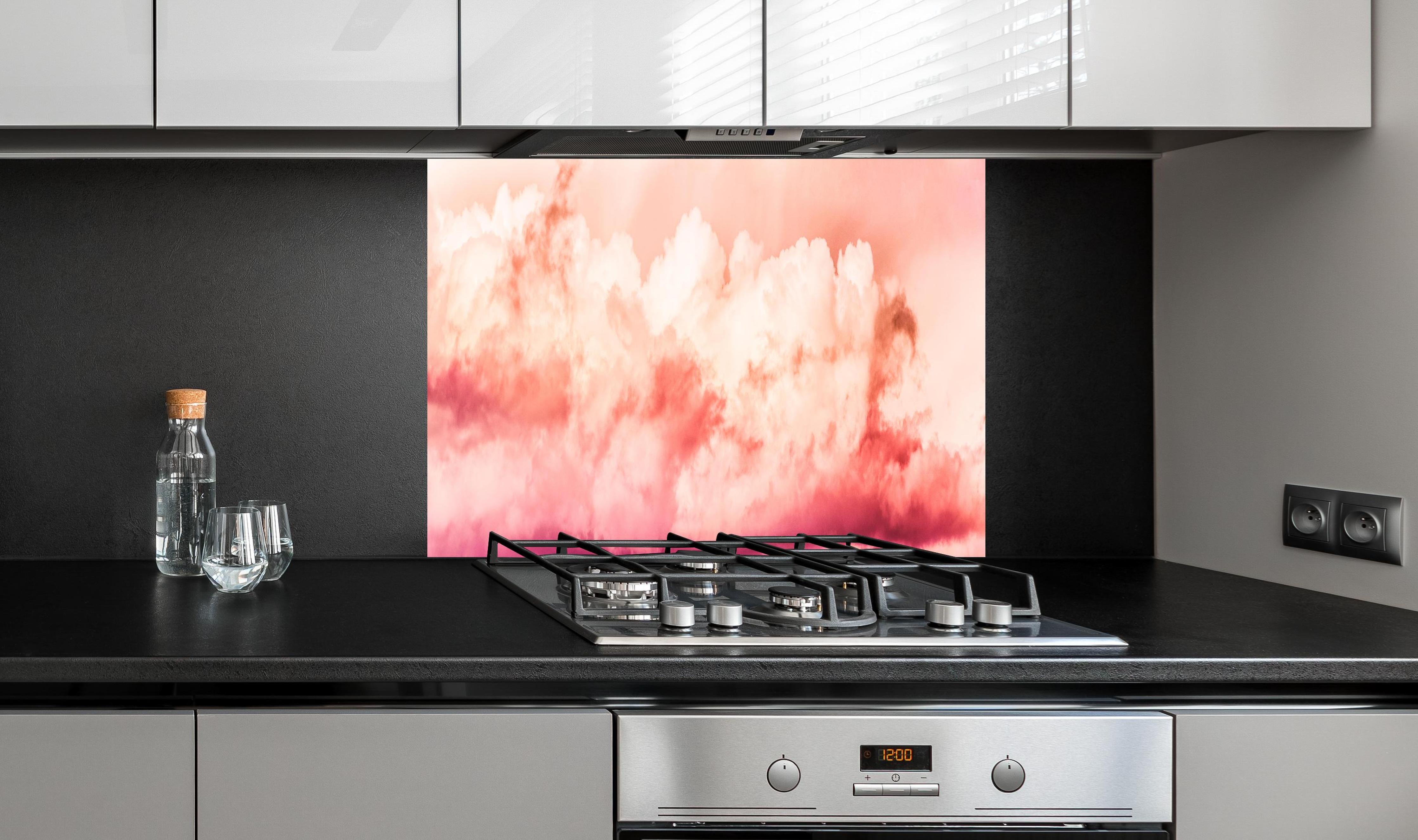 Spritzschutz - Rosa Wolkenhimmel hinter einem Cerankochfeld zwischen Holz-Kochutensilien
