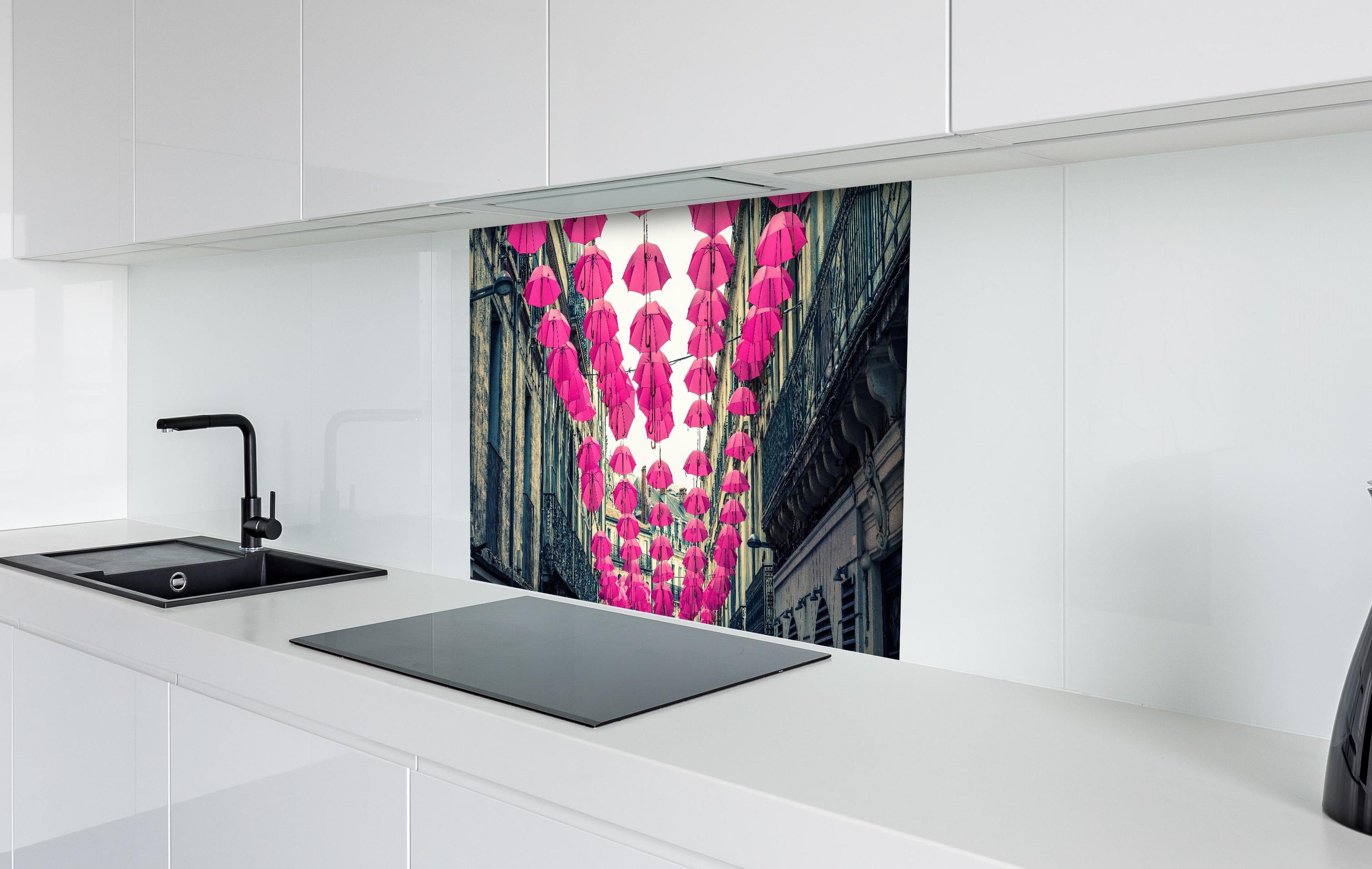 Spritzschutz - Rosafarbene Regenschirme als Straßenkunst hinter einem Cerankochfeld zwischen Holz-Kochutensilien
