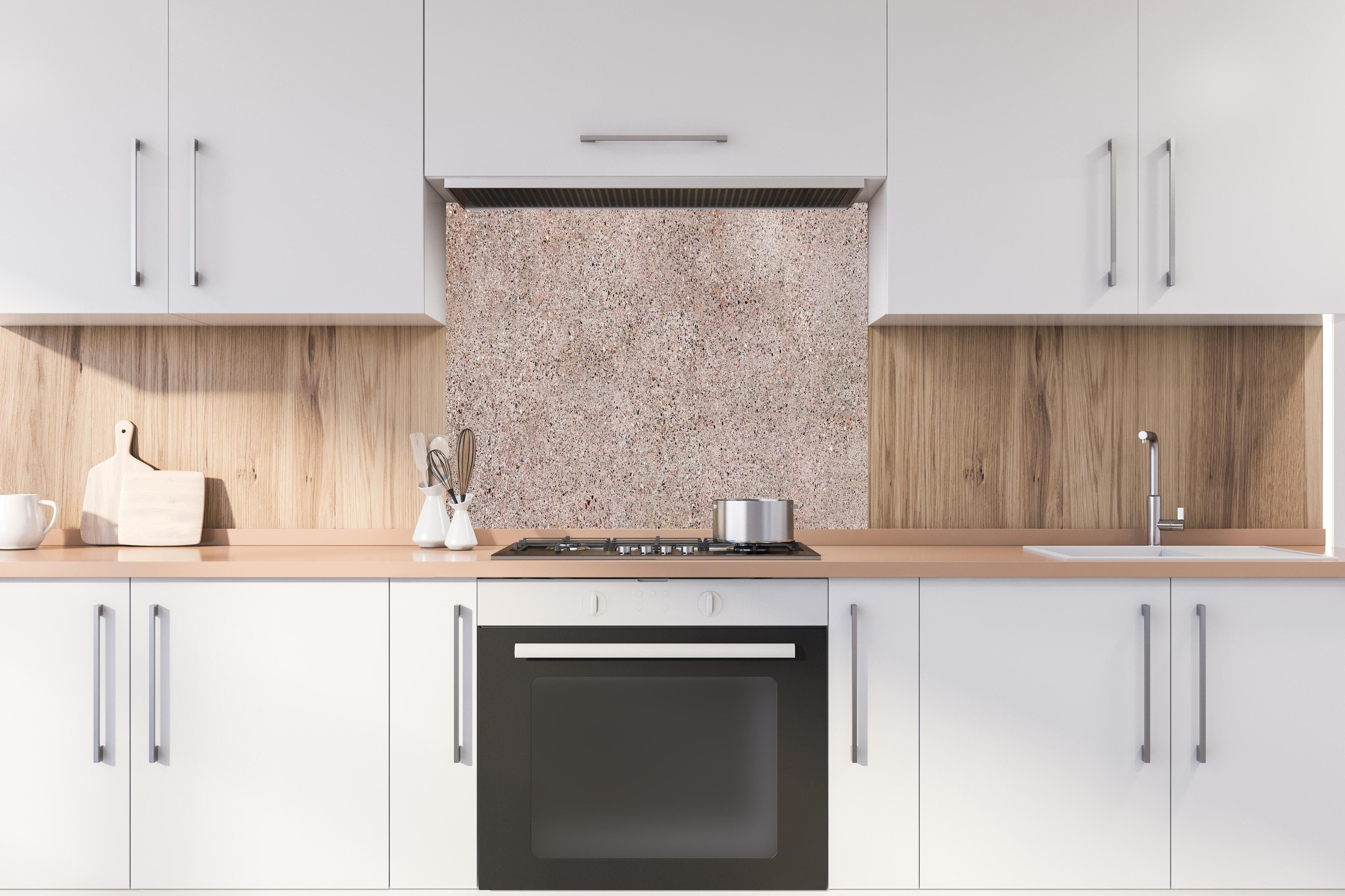 Spritzschutz - Rosafarbige natürliche Mosaiksteine hinter einem Cerankochfeld zwischen Holz-Kochutensilien
