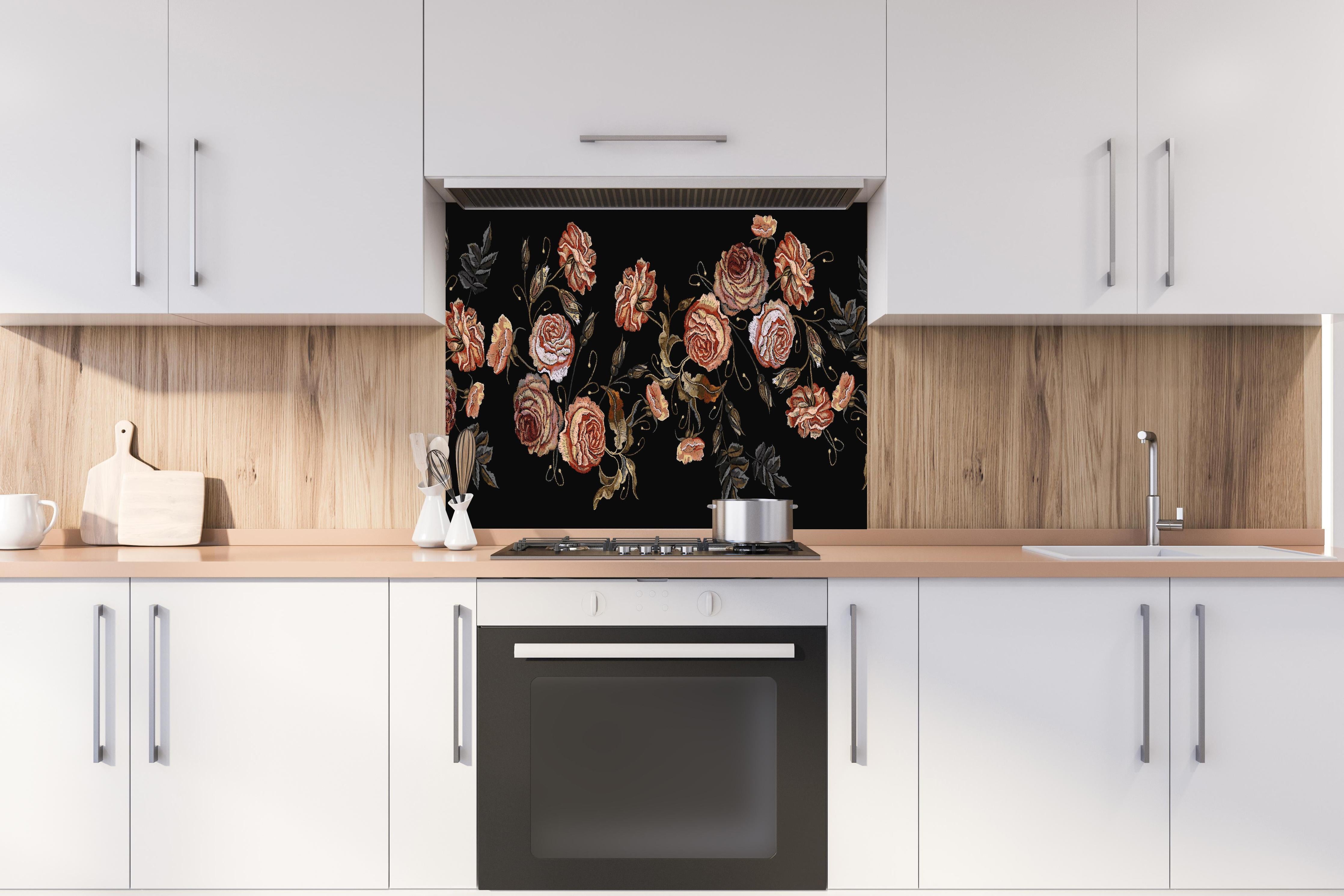 Spritzschutz - Rosen in der Dunkelheit hinter einem Cerankochfeld zwischen Holz-Kochutensilien
