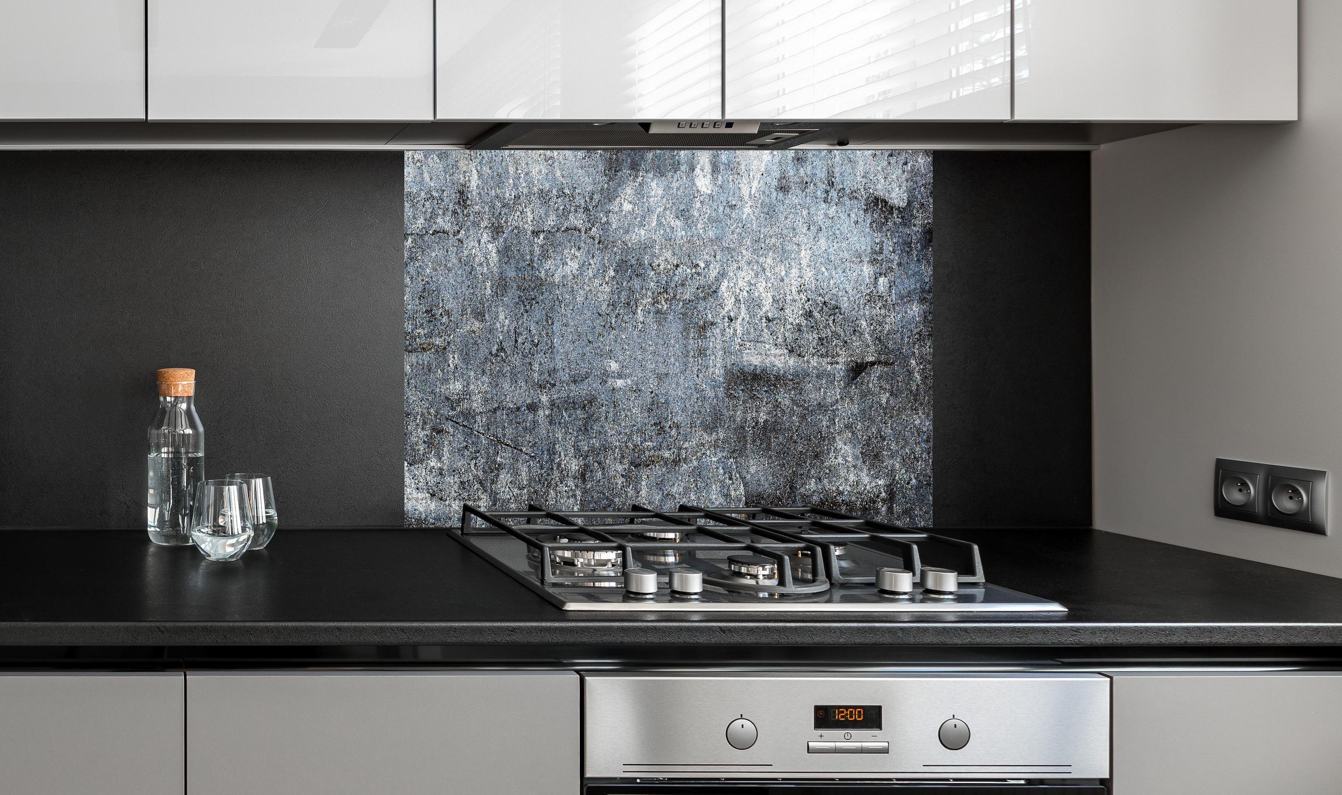 Spritzschutz - Rostiger Marmor aus Zement hinter einem Cerankochfeld zwischen Holz-Kochutensilien
