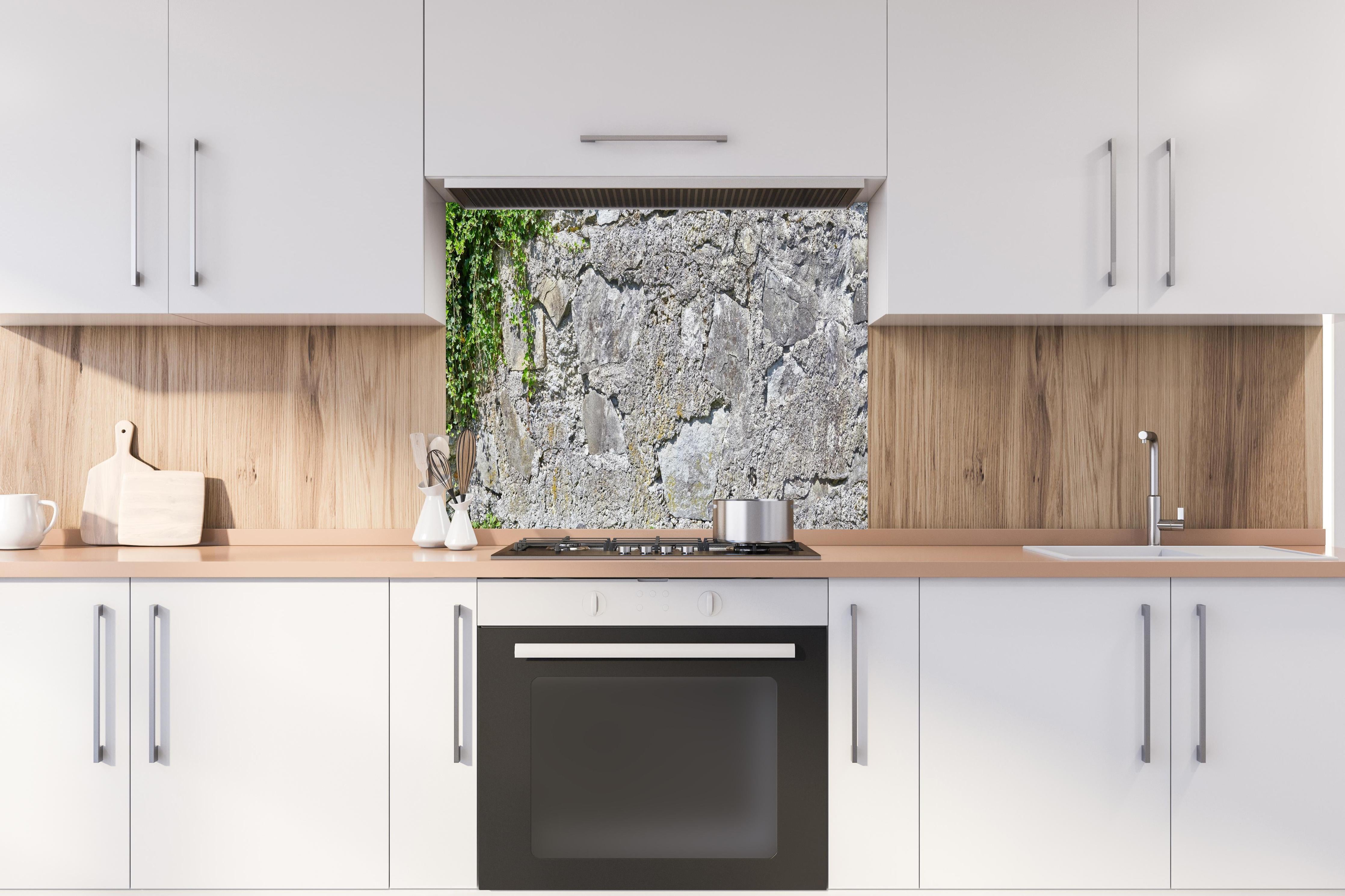 Spritzschutz - Rustikale Schiefermauer hinter einem Cerankochfeld zwischen Holz-Kochutensilien
