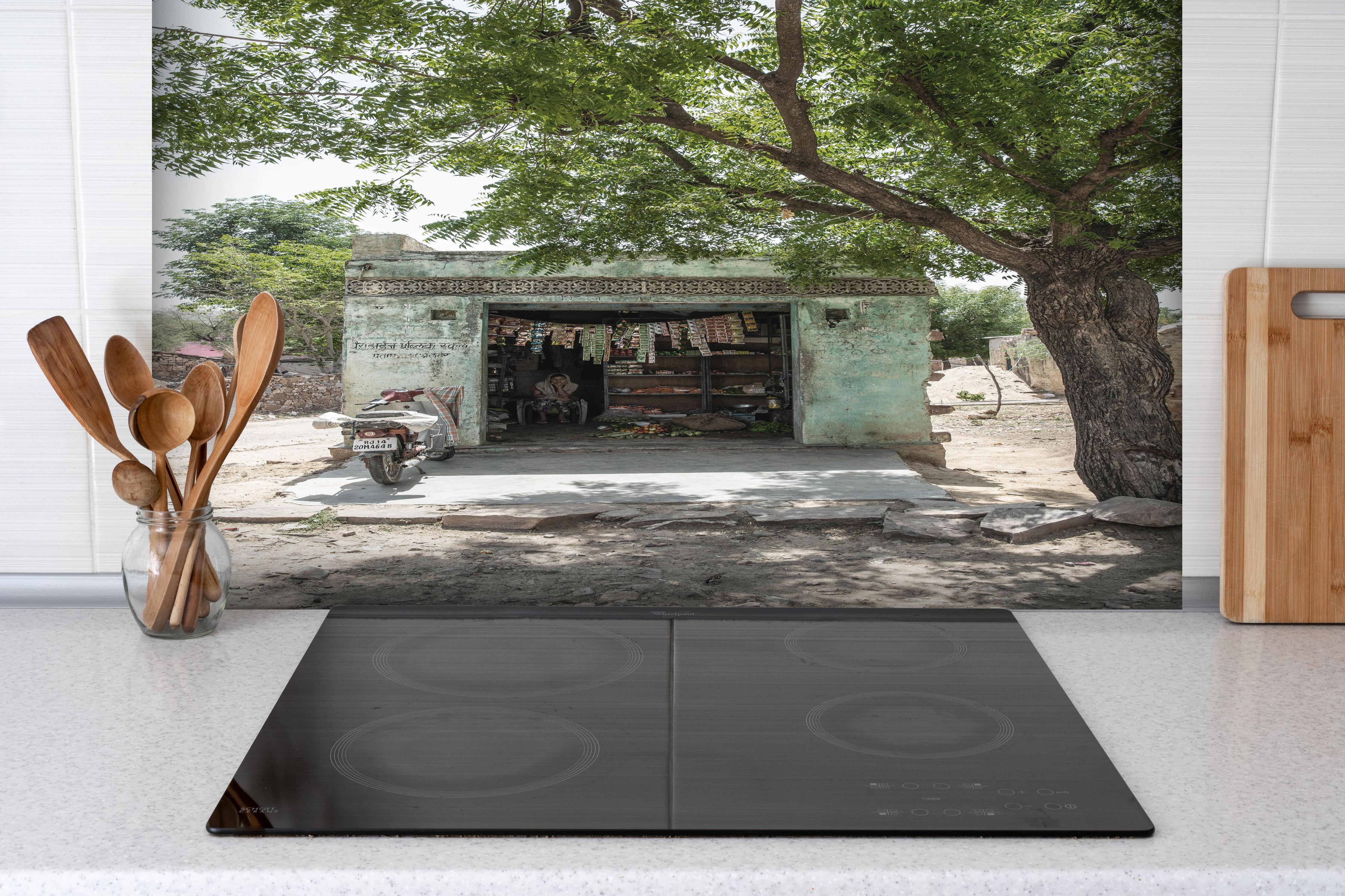 Spritzschutz - Rustikaler Laden unter Bäumen hinter einem Cerankochfeld zwischen Holz-Kochutensilien
