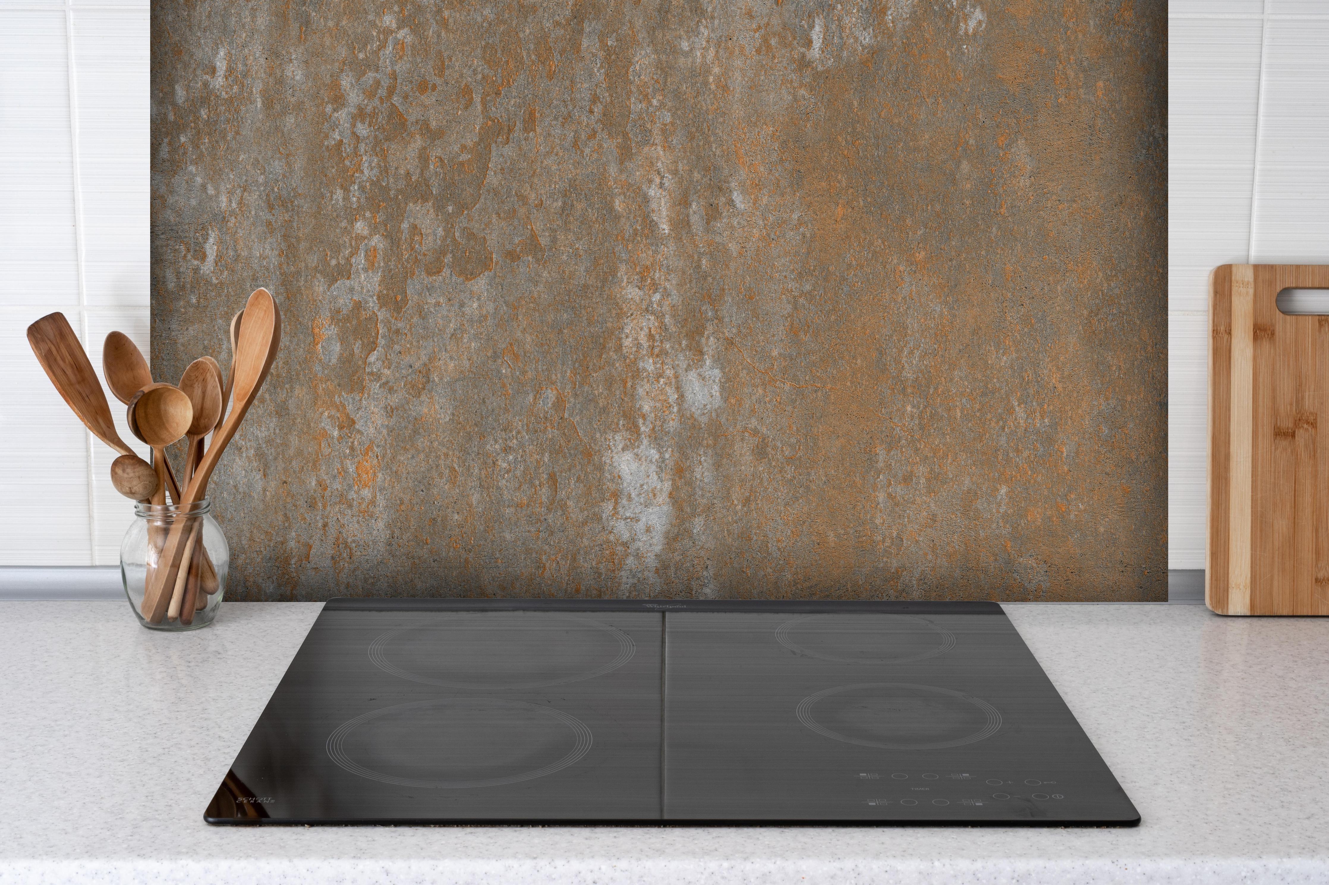 Spritzschutz - Rustikaler Stein Hintergrund hinter einem Cerankochfeld zwischen Holz-Kochutensilien

