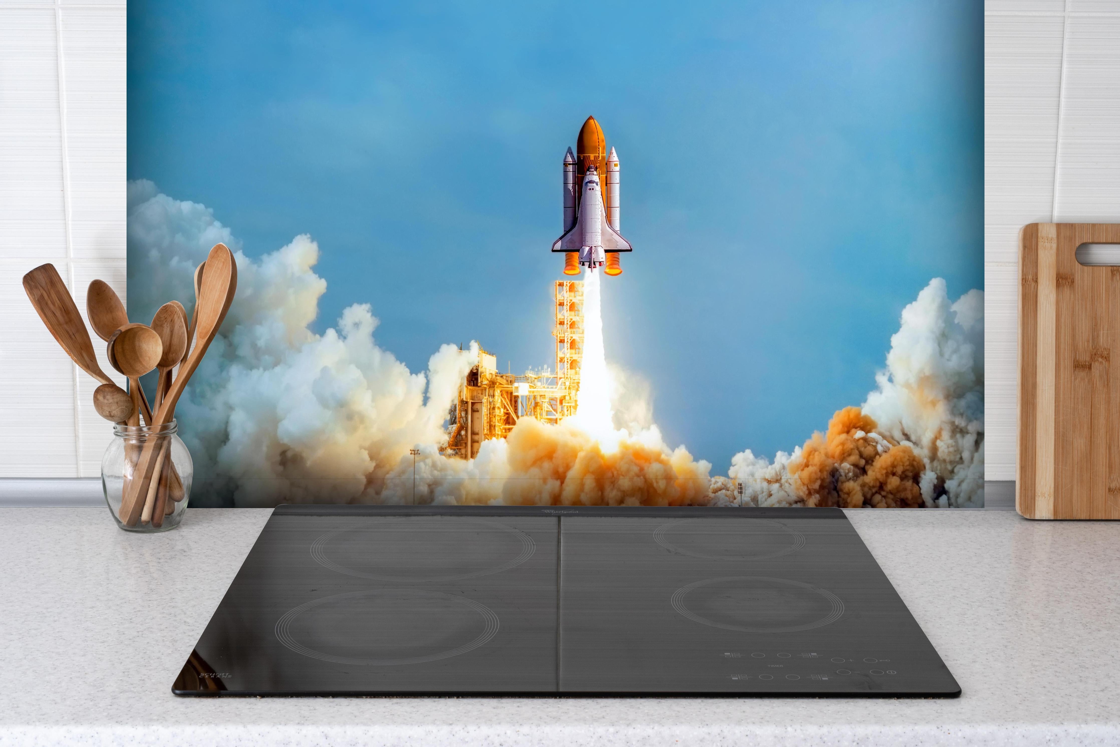 Spritzschutz - STS-135 Atlantis-Start hinter einem Cerankochfeld zwischen Holz-Kochutensilien
