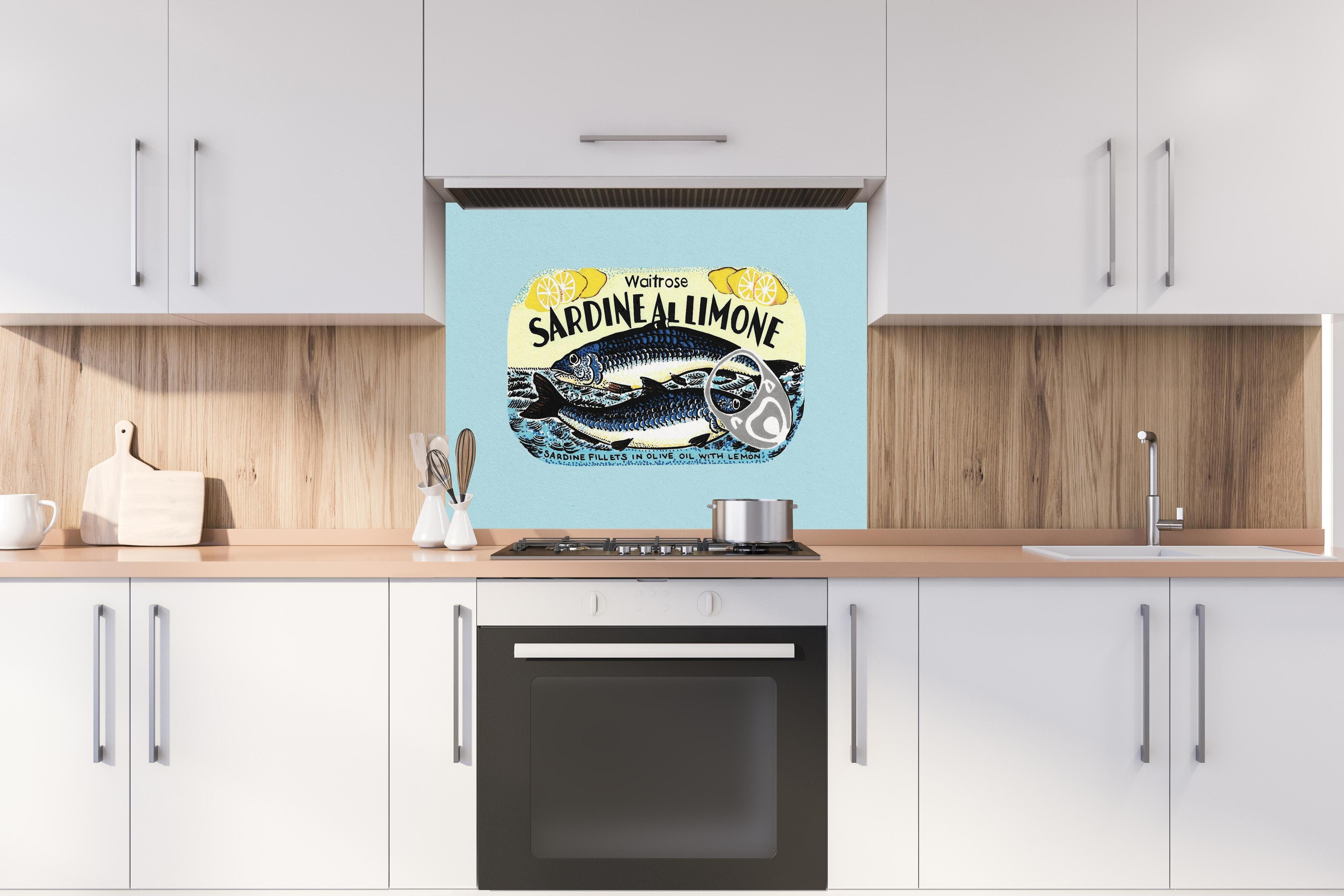 Spritzschutz - Sardine Al Limone hinter einem Cerankochfeld zwischen Holz-Kochutensilien
